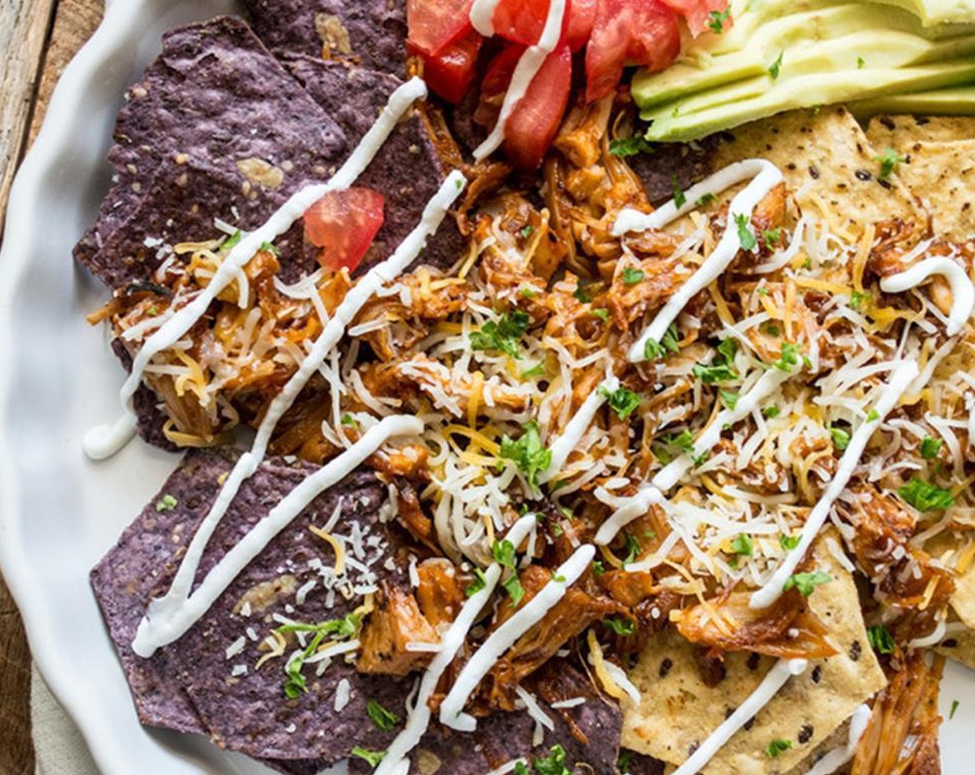 step 5 Once the jackfruit is ready, evenly divide it between two plates on the bed of Tortilla Chips (to taste). Top with Shredded Mexican Cheese Blend (1/2 cup), Tomato (1/2 cup), Avocado (1/2) and Sour Cream (to taste) then garnish with Fresh Herbs (to taste).