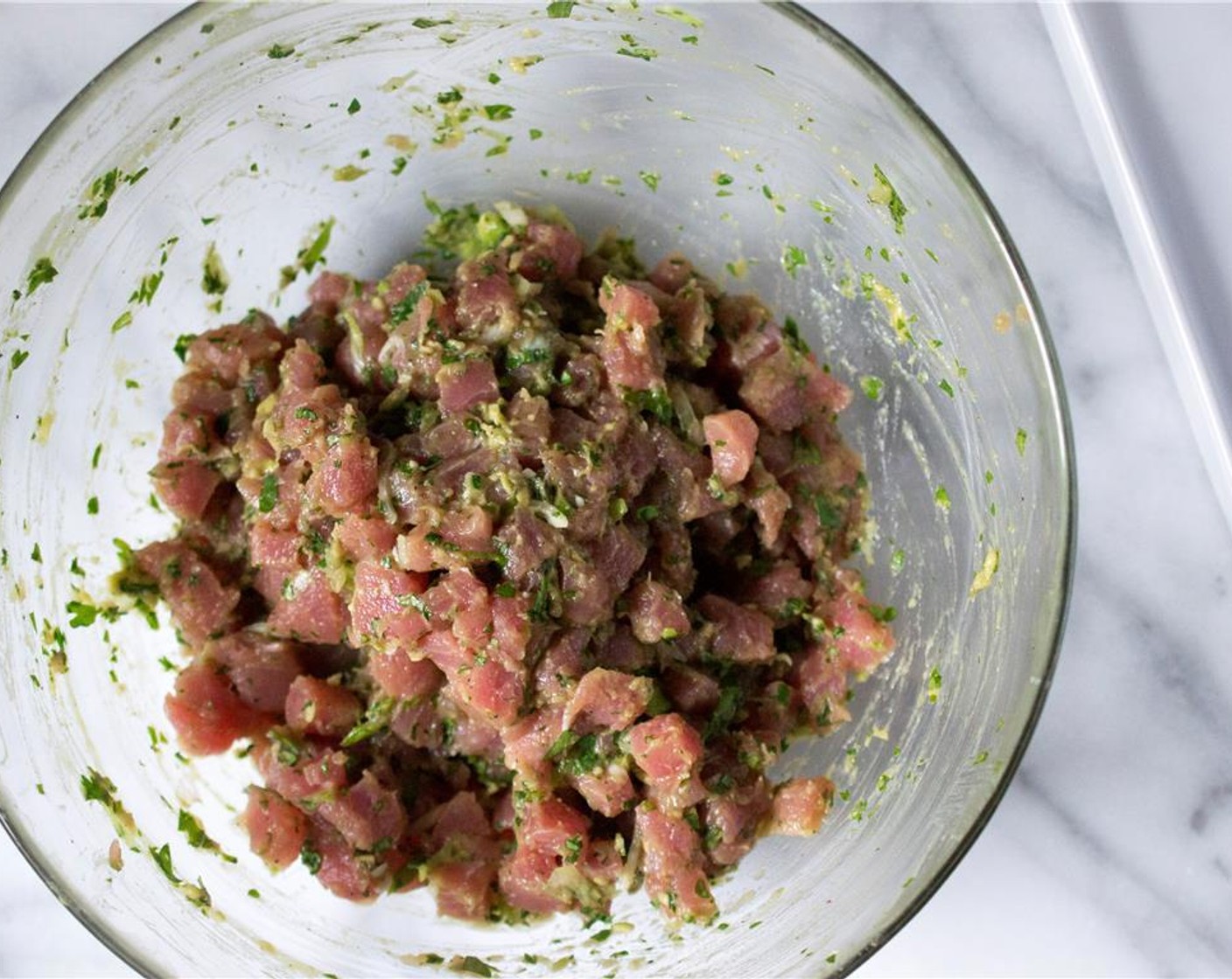 step 2 Add the Scallion (1 bunch), Fresh Cilantro (2 Tbsp), Fresh Ginger (1 tsp), Red Bird's Eye Chili Pepper (1), Avocado (1/2), Kosher Salt (3/4 tsp), and Ground Black Pepper (1/4 tsp) to the tuna. Gently work with your hands to incorporate all of the ingredients.