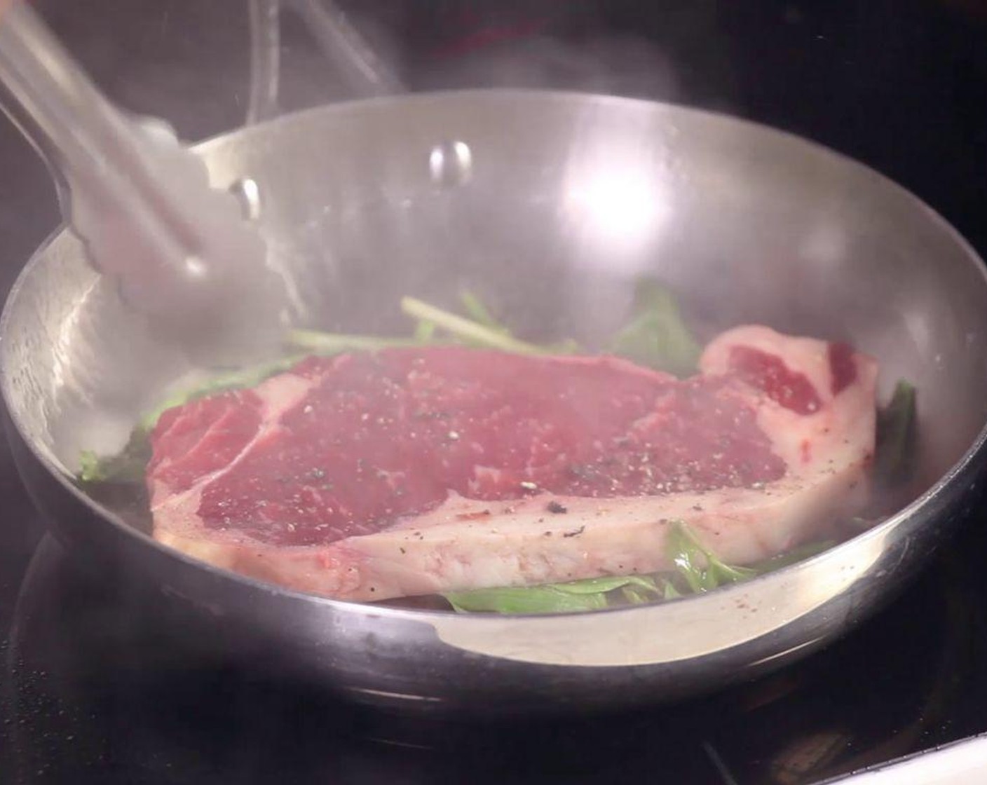 step 2 Add the Steak (9 oz) on top of basil leaves and cilantro to sear. Flip the steak. Keep on high heat until it turns brown.