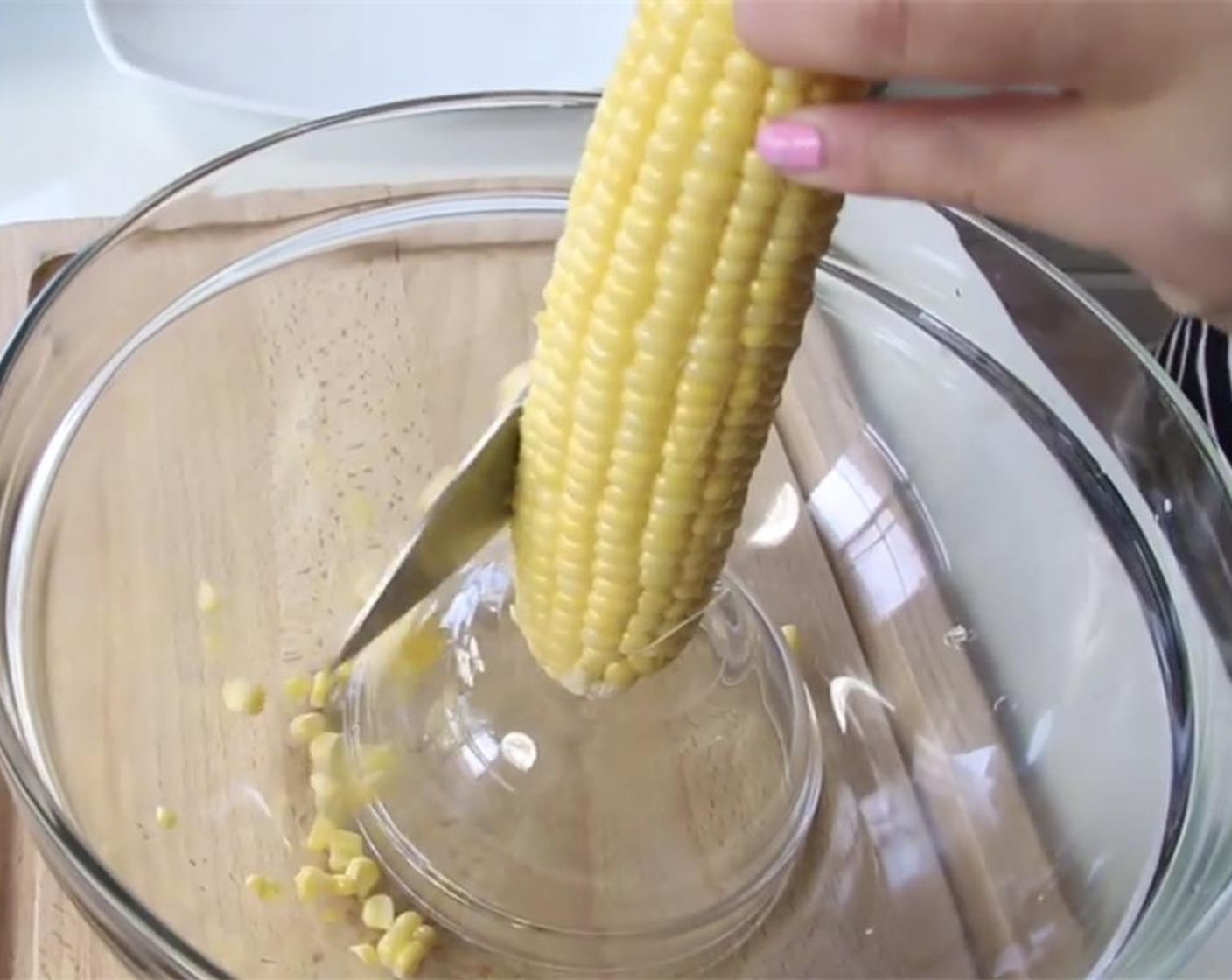 step 4 In a large bowl, invert a smaller bowl and stand the Corn (4 ears) on it. Shave the corn with your knife. This prevents to corn from flying everywhere. Save the corn cobs.