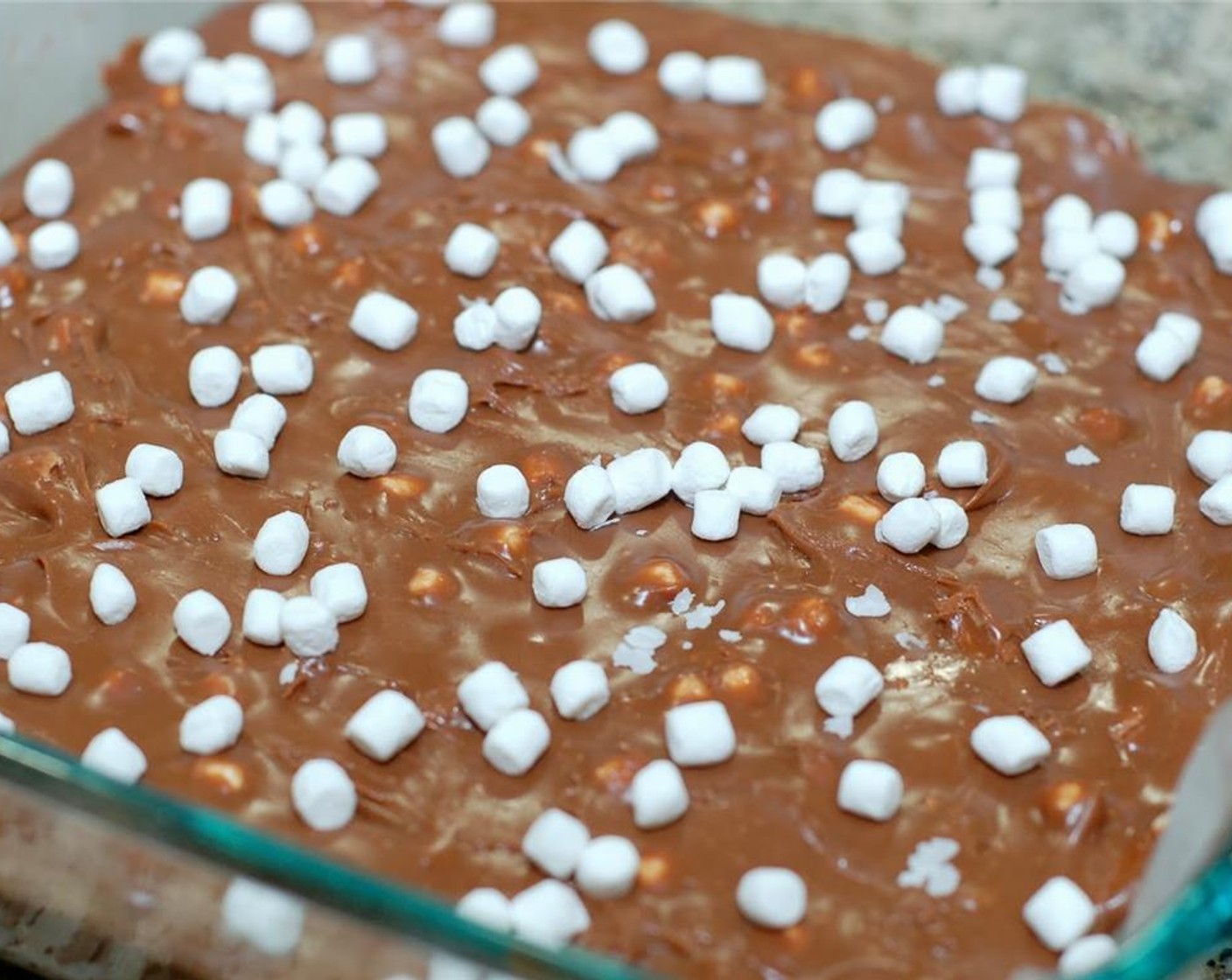 step 6 Then spread the mixture evenly onto a parchment paper lined 8″ x 8″ pan or glass dish. Sprinkle the top with Kraft® Jet-Puffed Mallow Bits, Vanilla (1 Tbsp).