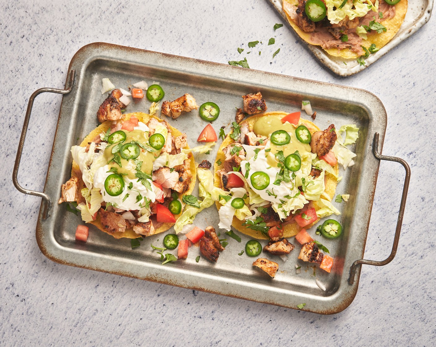 step 5 Assemble the tostadas on a baking sheet. Place Tostada Shells (6) on a baking sheet. Layer each one with refried beans, chopped chicken, Tomatoes (3), Red Onion (1), Lettuce (5 cups), Fresh Cilantro (1 bunch), Sour Cream (2 cups), Guacamole (1 cup), and Jalapeño Pepper (1/2 cup). Serve immediately.