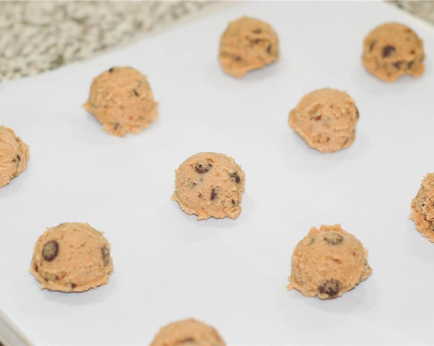 step 4 With a cookie scoop, place cookie dough mounds on a parchment lined, or greased, baking sheet, 2 inches apart. Bake 10 minutes, or until tops are golden brown. Cool for 2 minutes on sheet, then move them to a cooling rack. Enjoy!
