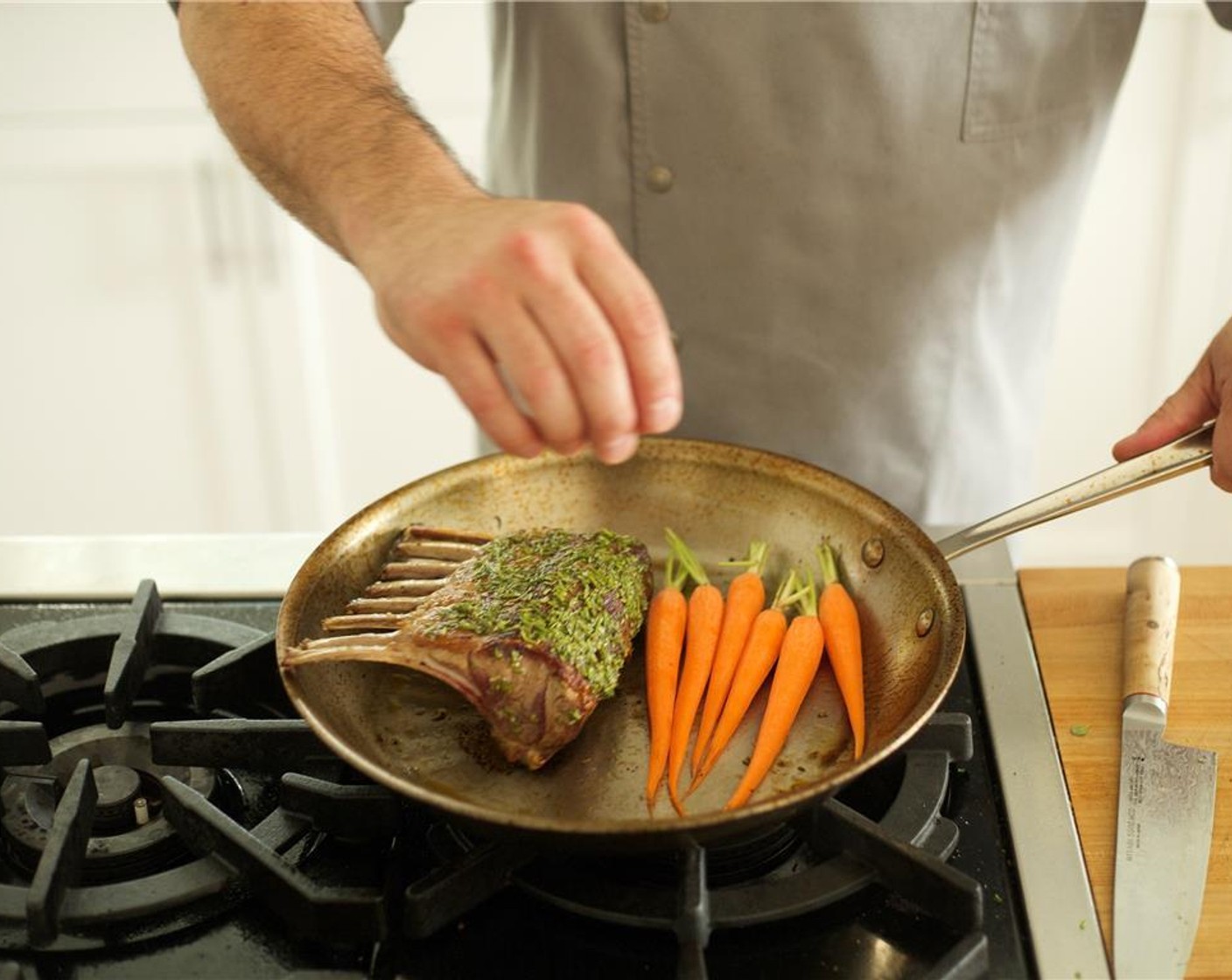 step 10 Carefully coat up grease with a paper towel by using your tongs and discard. Spread rosemary oil evenly over the lamb. Lay French Baby Carrots (6) next to lamb in pan.