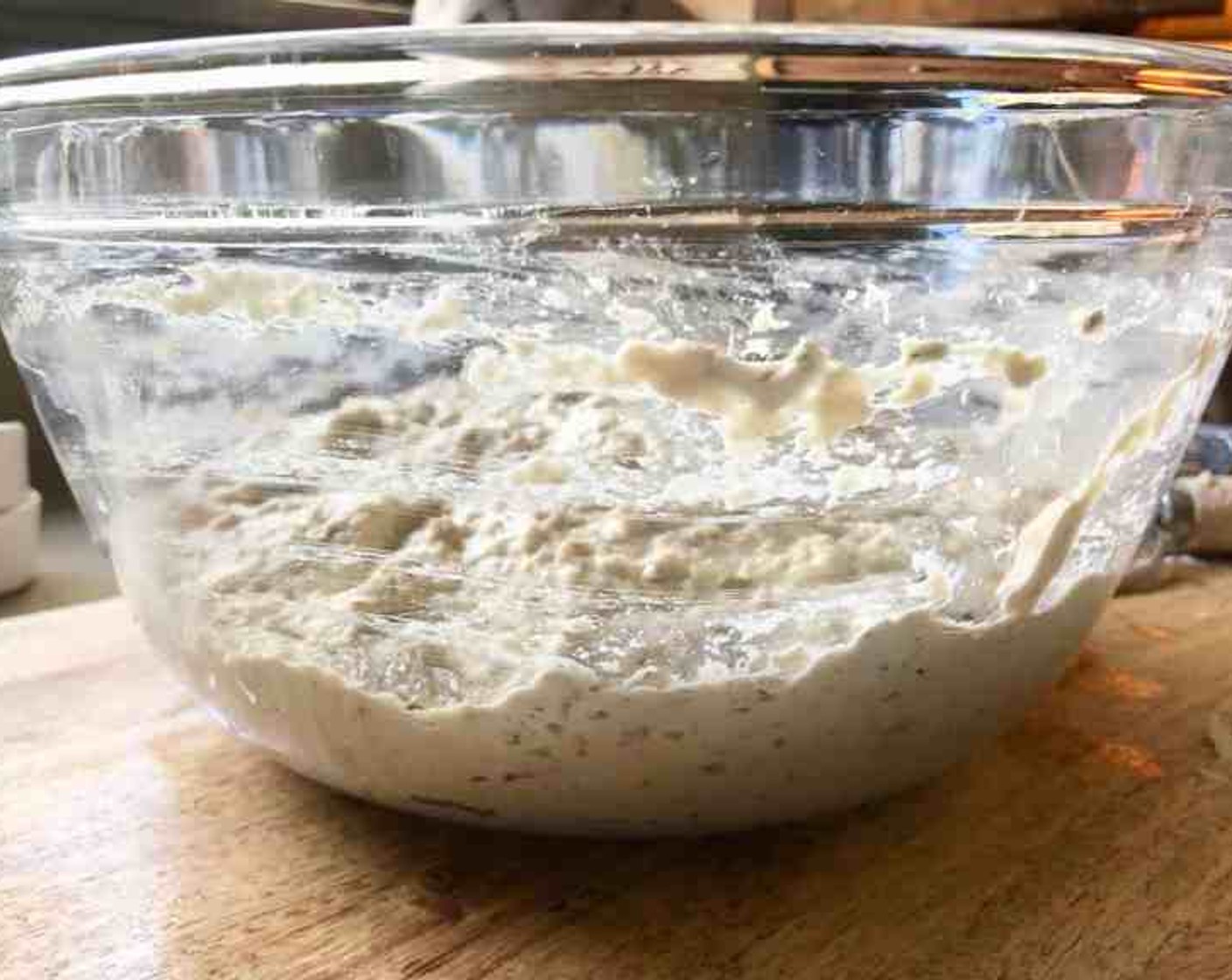 step 4 Loosely cover the container and let the dough hang out at room temperature until it begins to rise considerably. It will collapse or flatten a little on the top in about 2 hours.