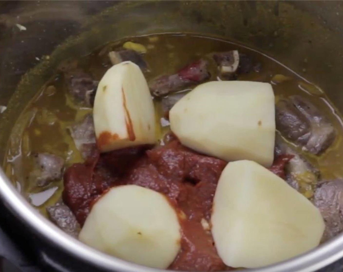 step 8 Place all the goat shoulder with all the meat juice into the pot. Add Tomato Paste (1/2 cup) on top of the goat shoulder. Do not stir. Add in the Potato (1).