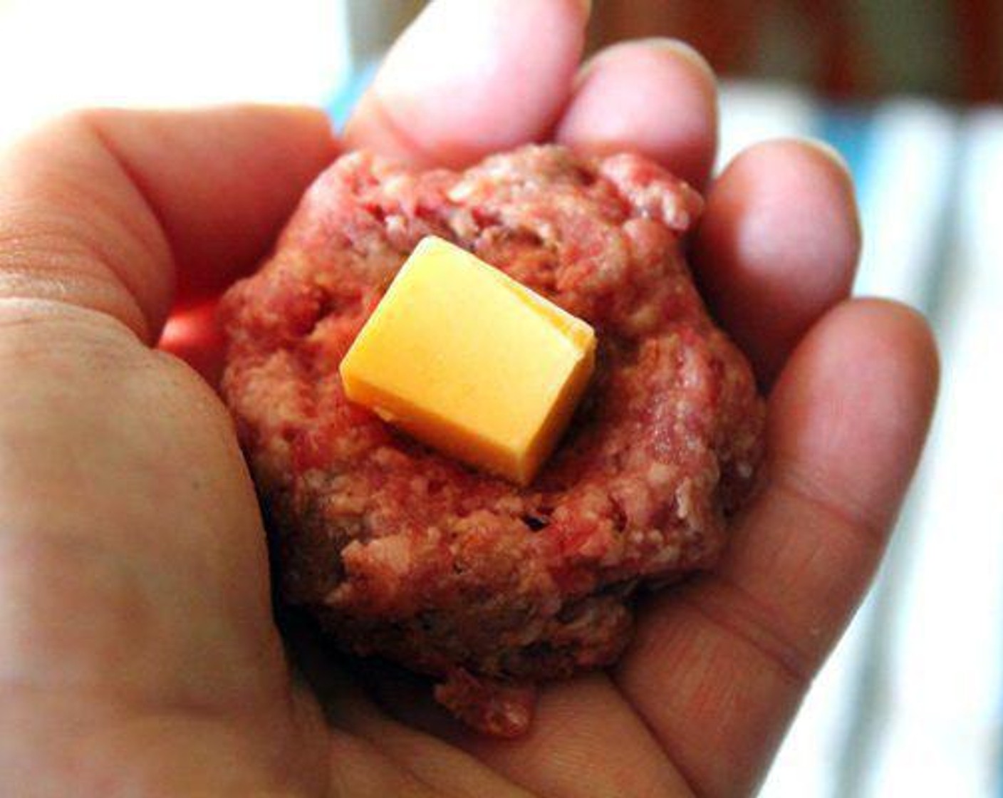 step 5 Evenly roll a section of the meat mixture into an approximately 1-inch sized meatball. Press 1 cube of cheese into the center. Gently form the meat around the cheese cube so it is in the center.