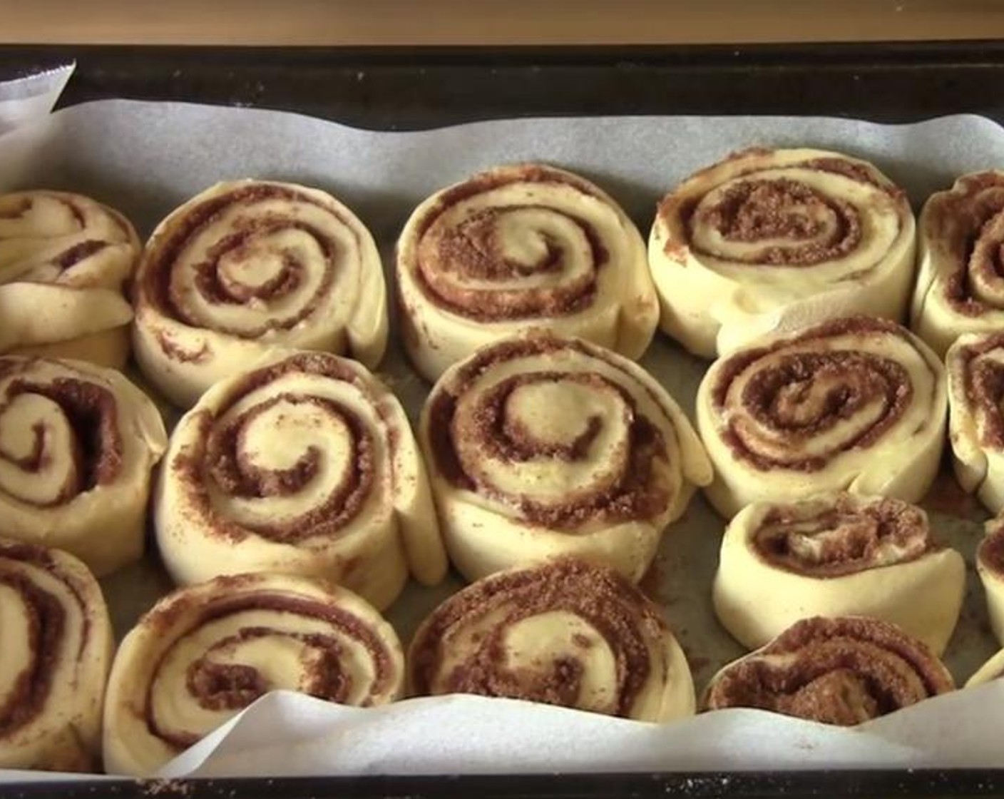 step 6 Taking on of the long ends, gently roll up the dough. Cut it into sixteen individual slices and put them into a tray lined with non stick baking paper. Cover it with a clean wrap and keep it at a warm spot for an hour.