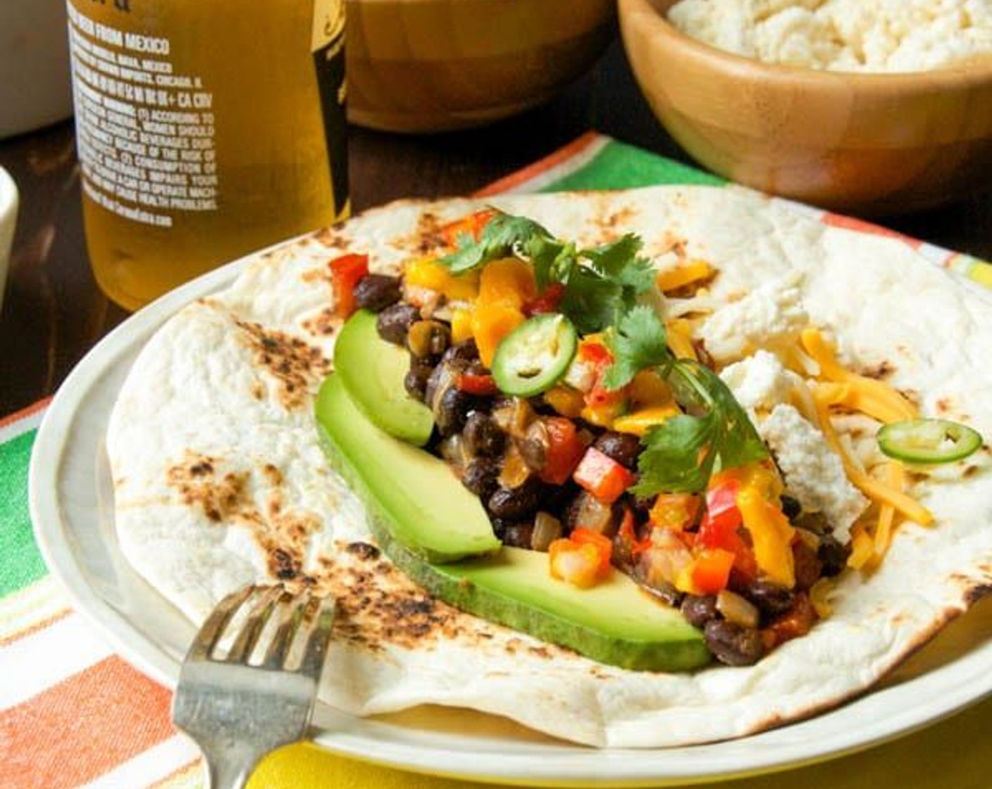 step 8 Assemble the tacos. Spoon the black beans into the tortilla shell. Tuck in a few slices of Avocado (1). Sprinkle with Cheddar Cheese (1/2 cup), top with mangoes salsa, Fresh Cilantro (1/2 cup) and lime wedge. Enjoy.
