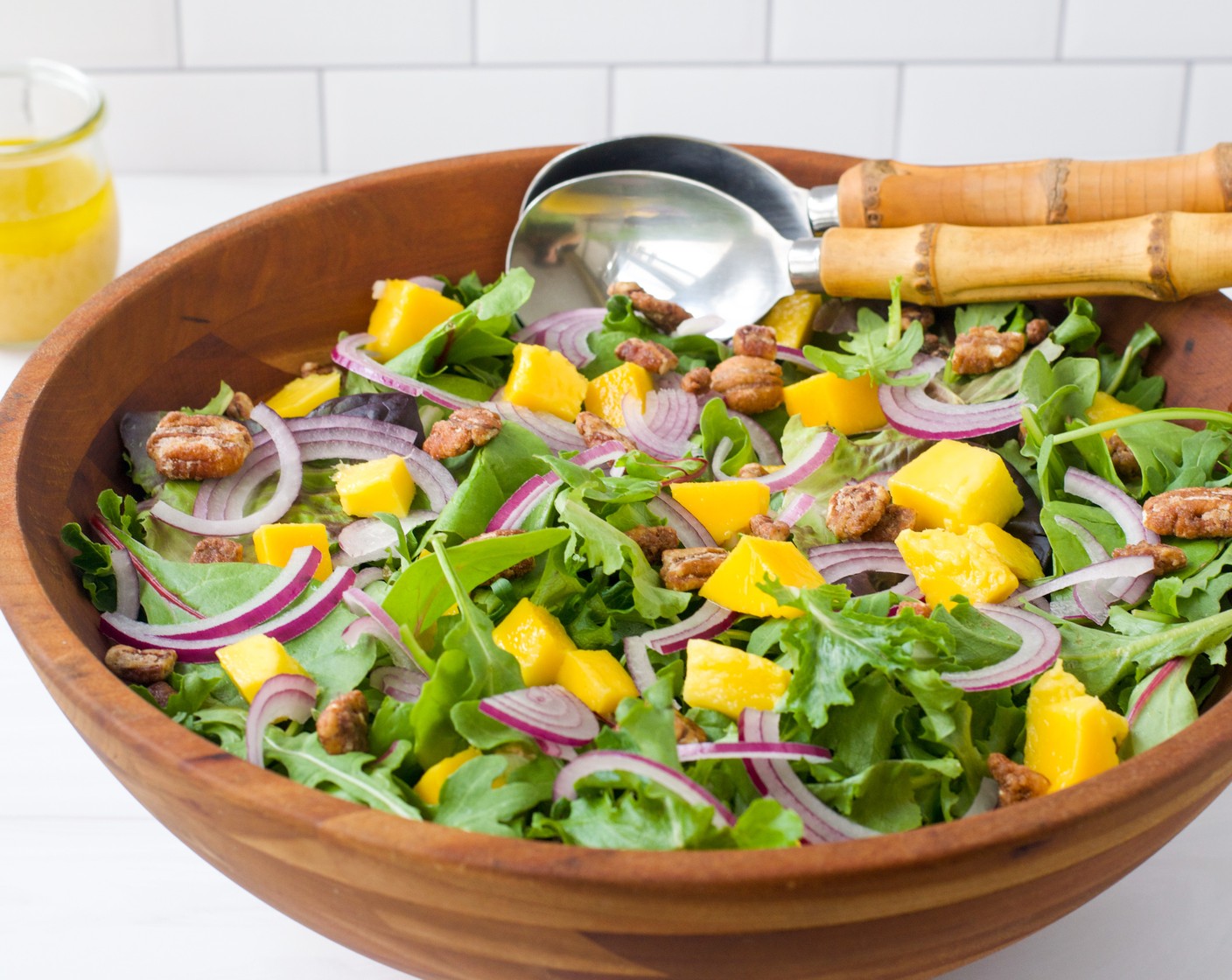 step 5 While the chicken is cooking, assemble the salad. Place the Baby Greens (9 1/2 cups) in a large bowl. Top with Mango (1), Red Onion (1/2), and Candied Pecans (1 cup). Dress the salad and toss gently to combine. Divide the salad among four dinner plates.
