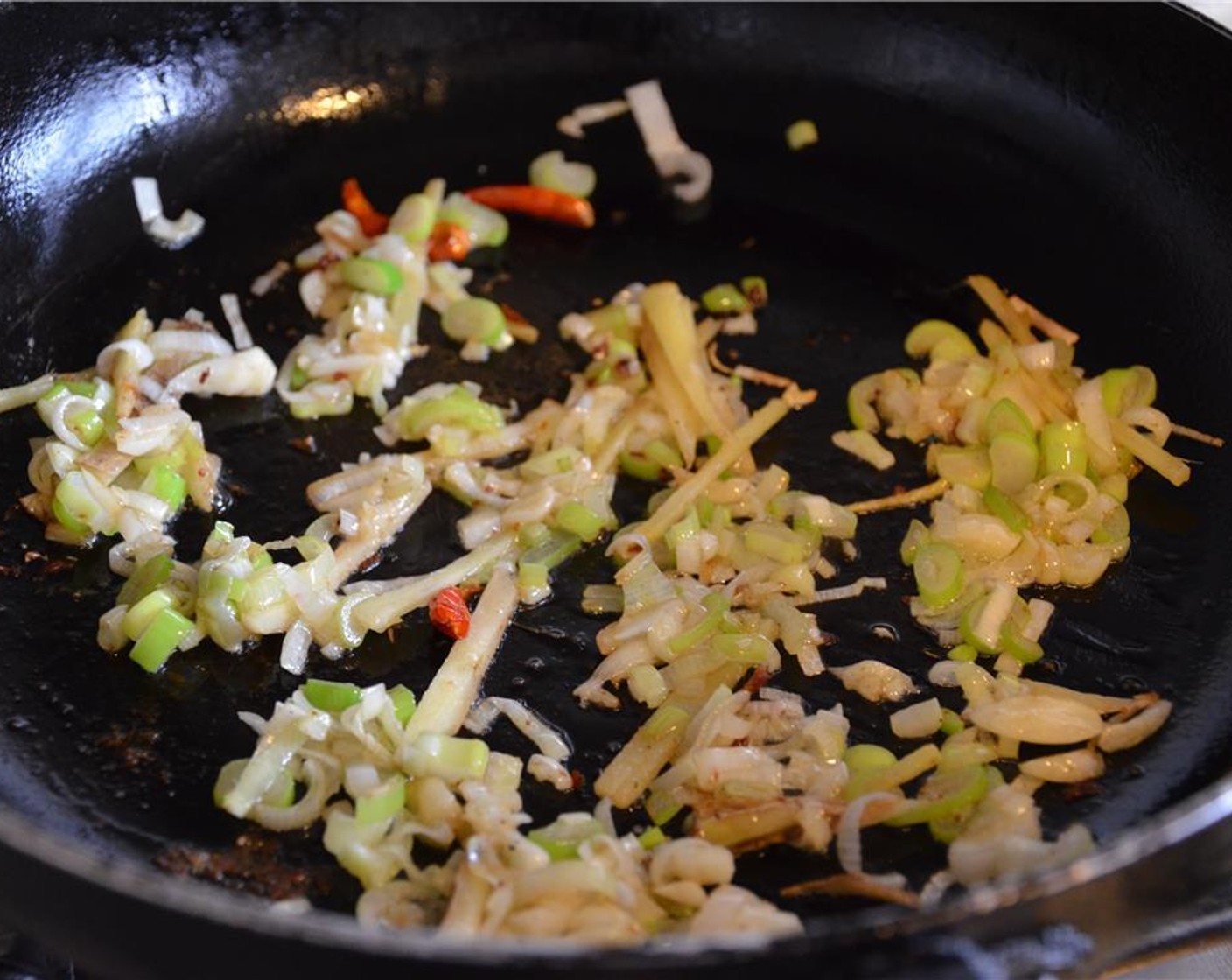 step 7 Add Canola Oil (1 Tbsp) to the wok, swirling to coat bottom and sides. Add chiles, ginger, garlic, and leek and cook, tossing constantly, until fragrant, about 30 seconds.