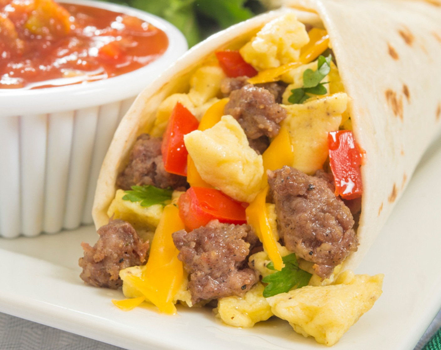 step 5 To assemble your burritos, spread a thin layer of Fat-Free Sour Cream (1/4 cup) on each tortilla and top with even amounts of all ingredients: eggs, peppers and onions, sausage, Shredded Reduced-Fat Cheddar Cheese (1/2 cup) and Salsa (1/2 cup). Roll and serve.