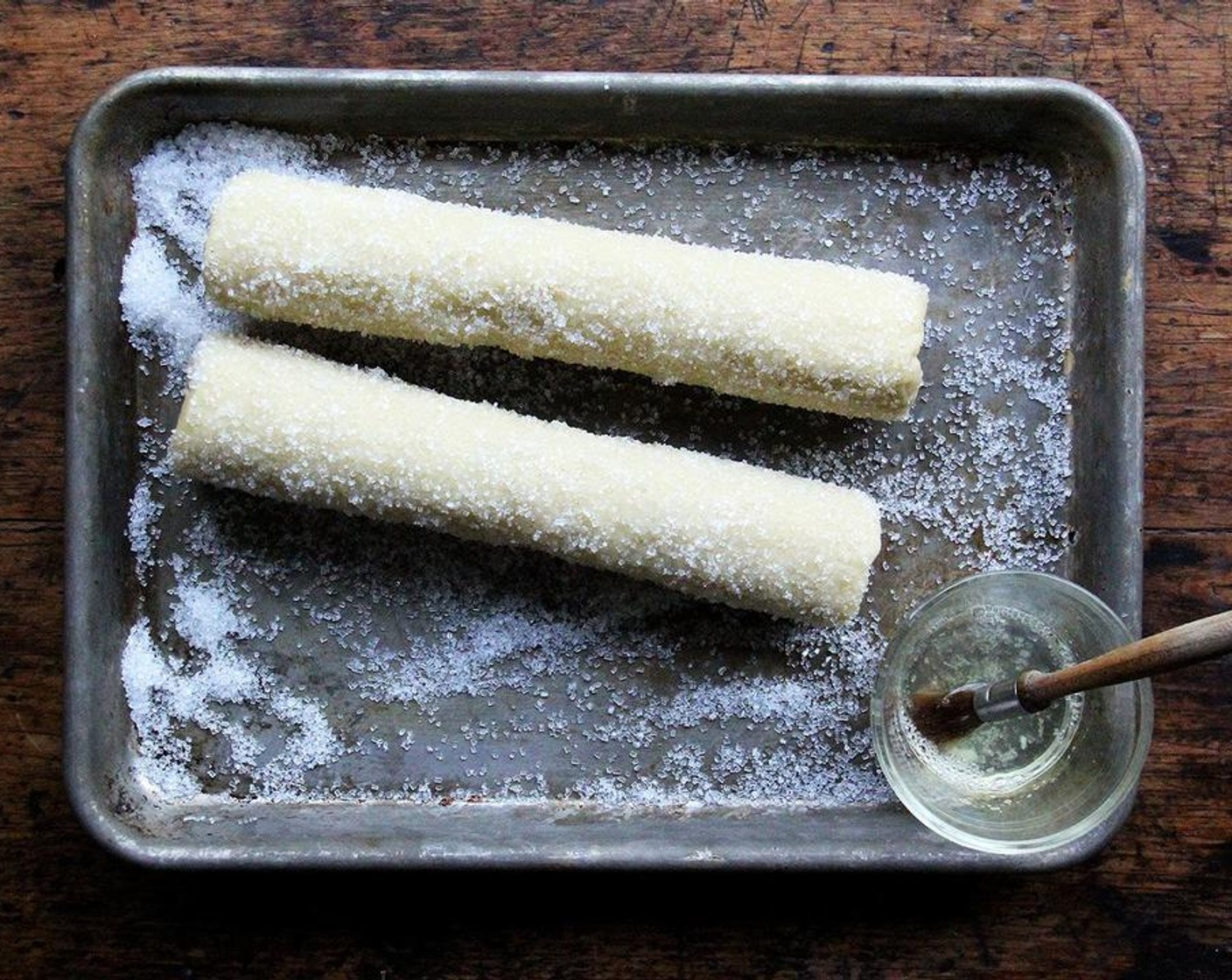 step 5 When you’re ready to bake, preheat the oven to 325 degrees F (160 degrees C). Line a baking sheet with parchment paper or a silicone baking mat. Add a splash of cold water to the Egg White and mix with a fork to blend. Brush each log with this egg wash and roll it in Sanding Sugar (to taste) until it’s evenly coated.