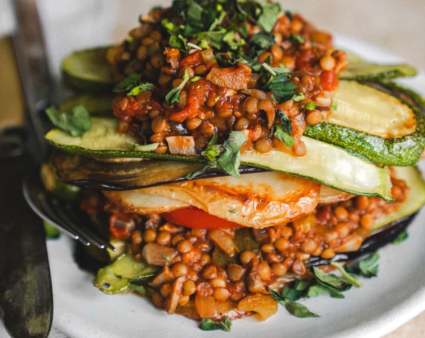 step 7 To assemble, place a layer of potatoes onto a plate, then some zucchini, eggplant, lentil meat sauce, Tomatoes (as needed) and repeat one more time. Garnish with fresh parsley and your choice of fixings.