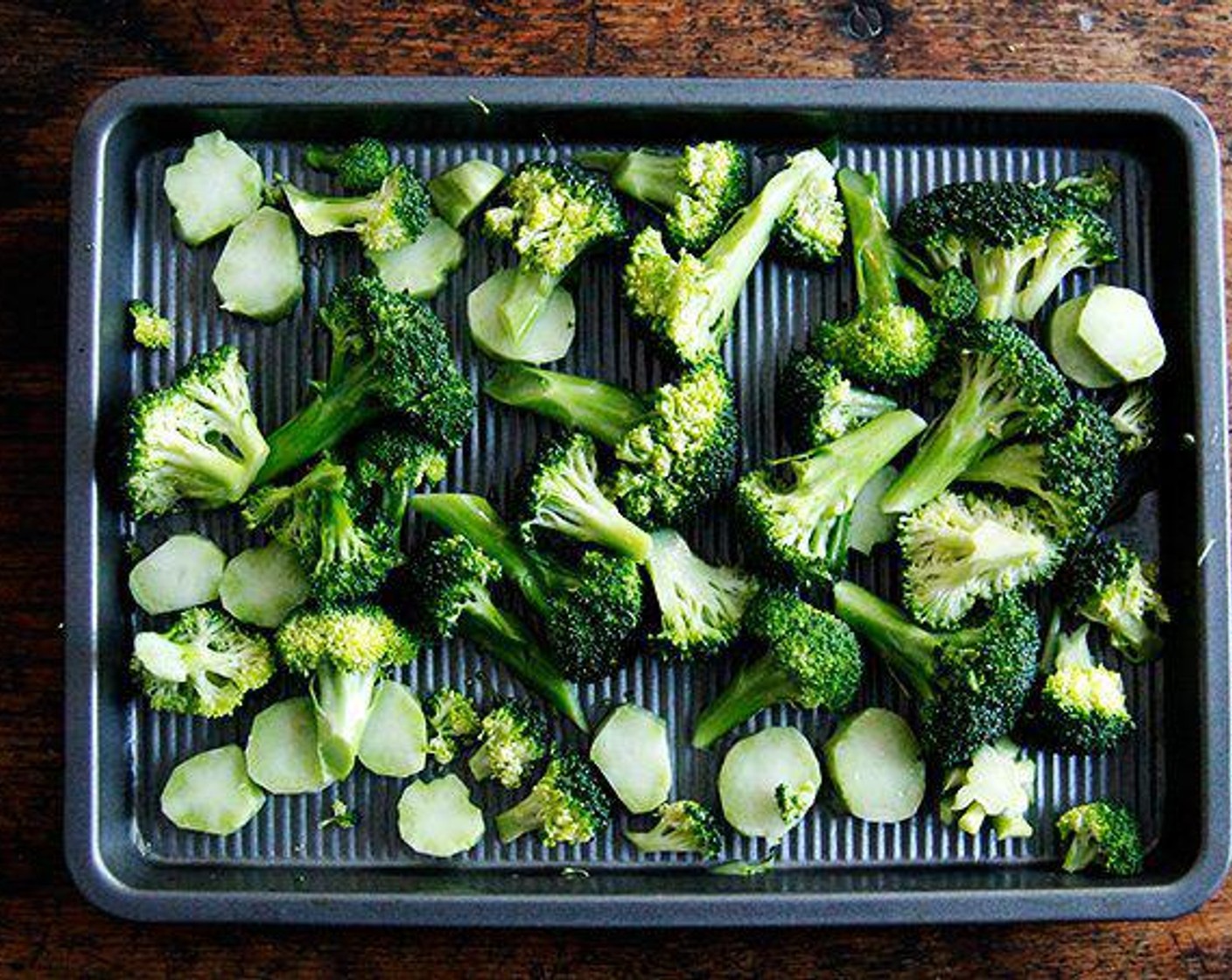 step 4 Drizzle Olive Oil (1 Tbsp) over the bare sheet pan, swirl it to coat, scatter the broccoli over top, drizzle with another tablespoon of Olive Oil, season generously with Salt (to taste) and Ground Black Pepper (to taste), and toss to coat with your hands. Spread into an even layer.