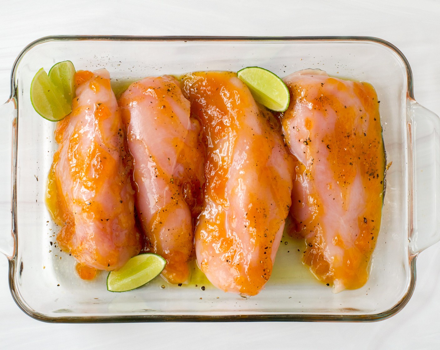step 3 Pat the Boneless, Skinless Chicken Breasts (4) dry with paper towels. Season each chicken breast with Kosher Salt (1/2 tsp) and Ground Black Pepper (1/2 tsp) and then brush 1 Tbsp of the Mango-Peach Preserves (4 Tbsp) over each breast. Place the chicken in the prepared baking dish and tuck the Lime (1) wedges around the chicken. Cover with the parchment paper, oiled side down.