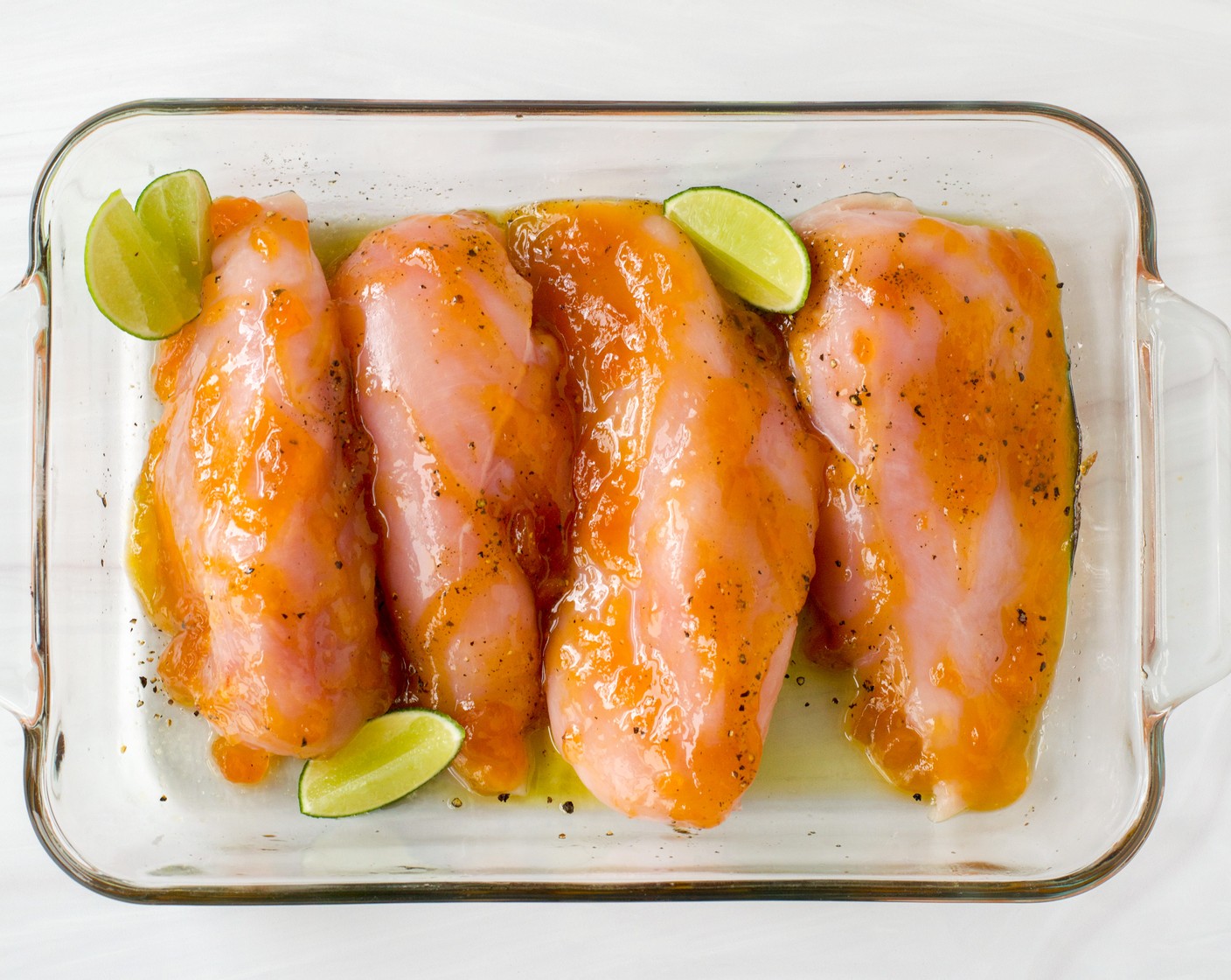 step 3 Pat the Boneless, Skinless Chicken Breasts (4) dry with paper towels. Season each chicken breast with Kosher Salt (3/4 tsp) and Ground Black Pepper (1/2 tsp) and then brush 1 Tbsp of the Mango-Peach Preserves (1/4 cup) over each breast. Place the chicken in the prepared baking dish and tuck the Lime (1) wedges around the chicken. Cover with the parchment paper, oiled side down.