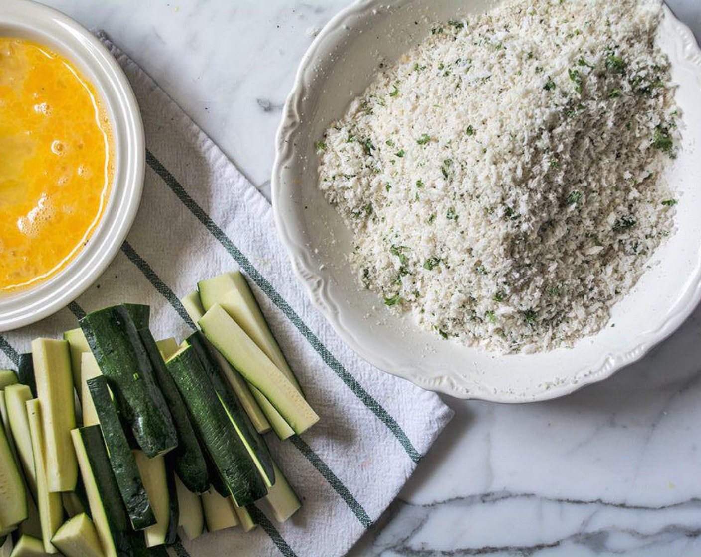 step 4 In a separate bowl, add Farmhouse Eggs® Large Brown Eggs (2) and beat well. Dip each piece of Zucchini (4) in the eggs, then coat in the panko and parmesan mix, before adding to aluminum-lined baking sheet. Repeat with all zucchini strips and spread out in a single layer.