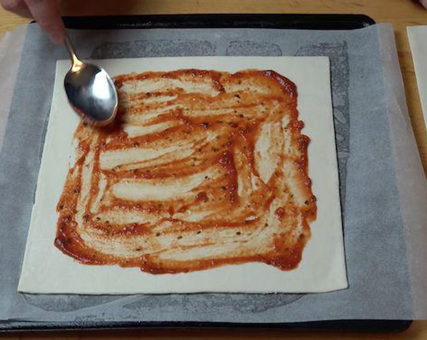 step 2 Add Pizza Sauce (2 Tbsp) to the center of each puff pastry sheet and using a spoon spread it out but leave a border around the edge.