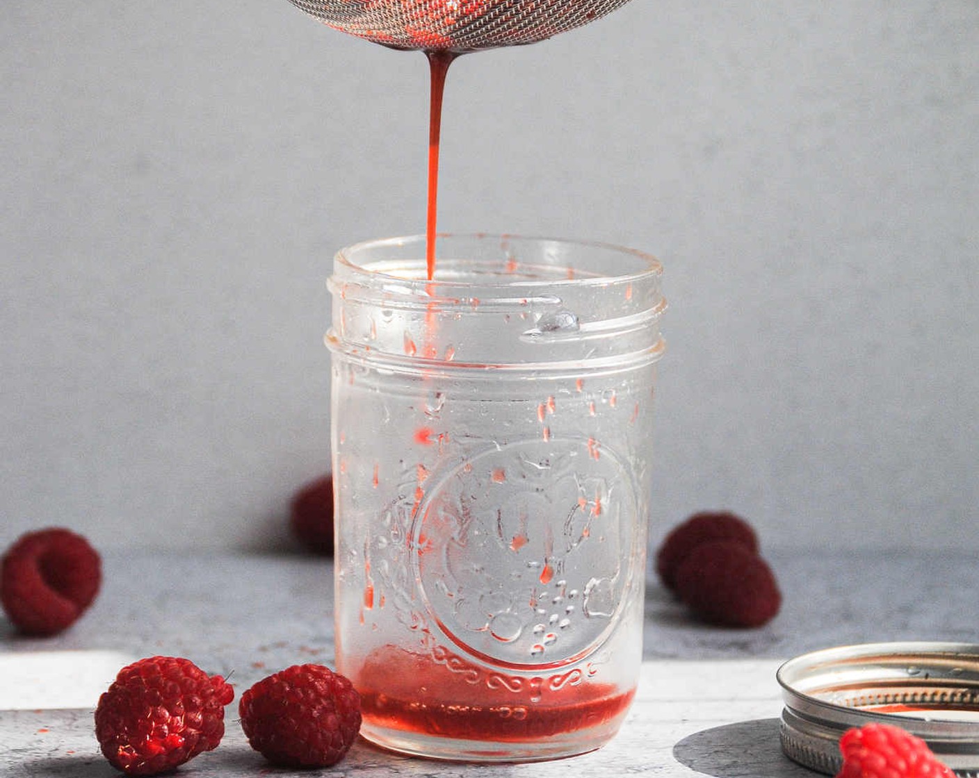 step 3 Pour simple syrup into a glass through a sieve. Use a spatula to push down on the raspberries in the sieve, expressing as much raspberry juice as possible into the glass.