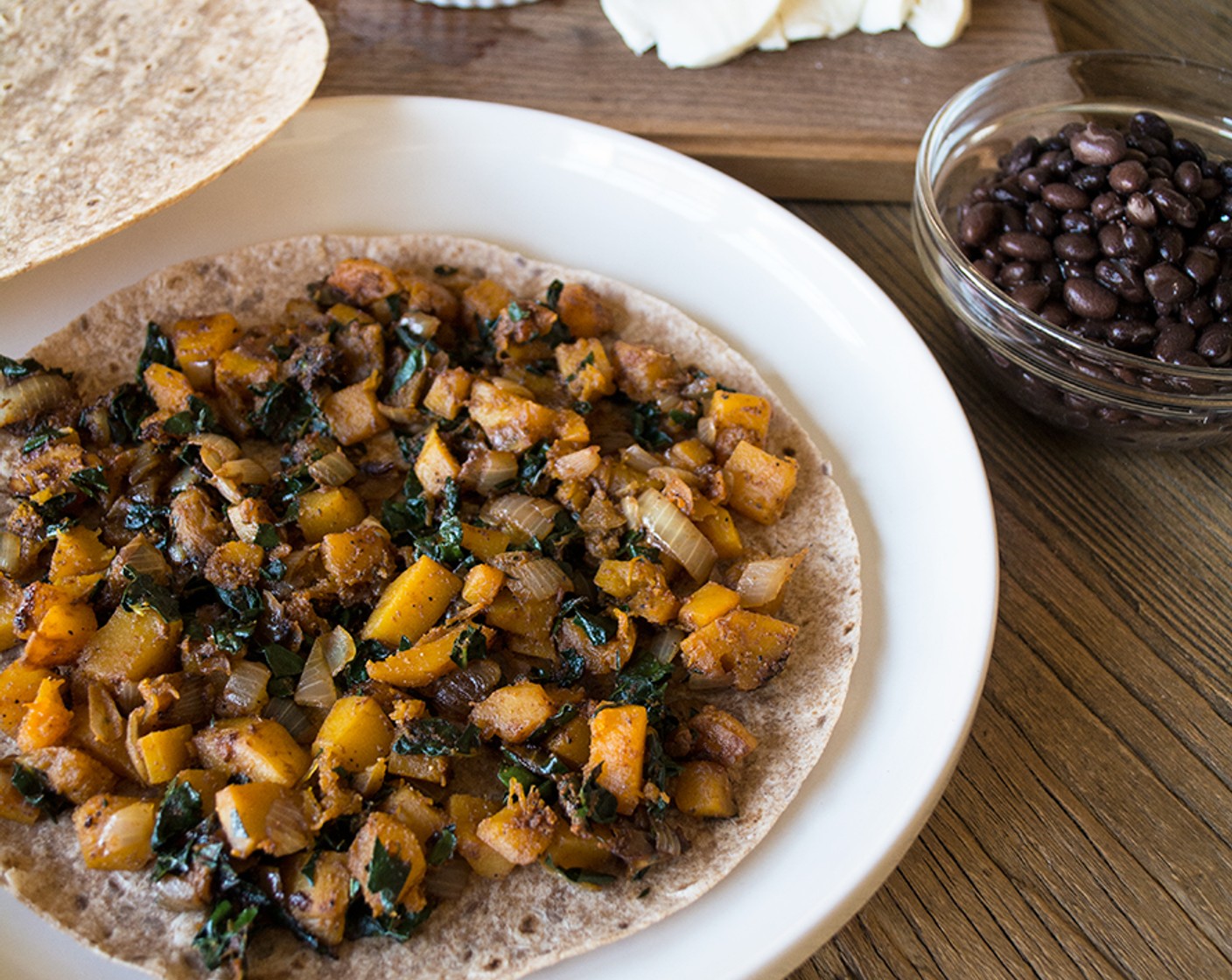 step 3 Spread out half of the cooked veggies, then top with one-quarter Canned Black Beans (1/2 cup) and approximately Shredded 2% Mozzarella Cheese (1/2 cup) on one Whole Grain and Flax Tortillas (4).