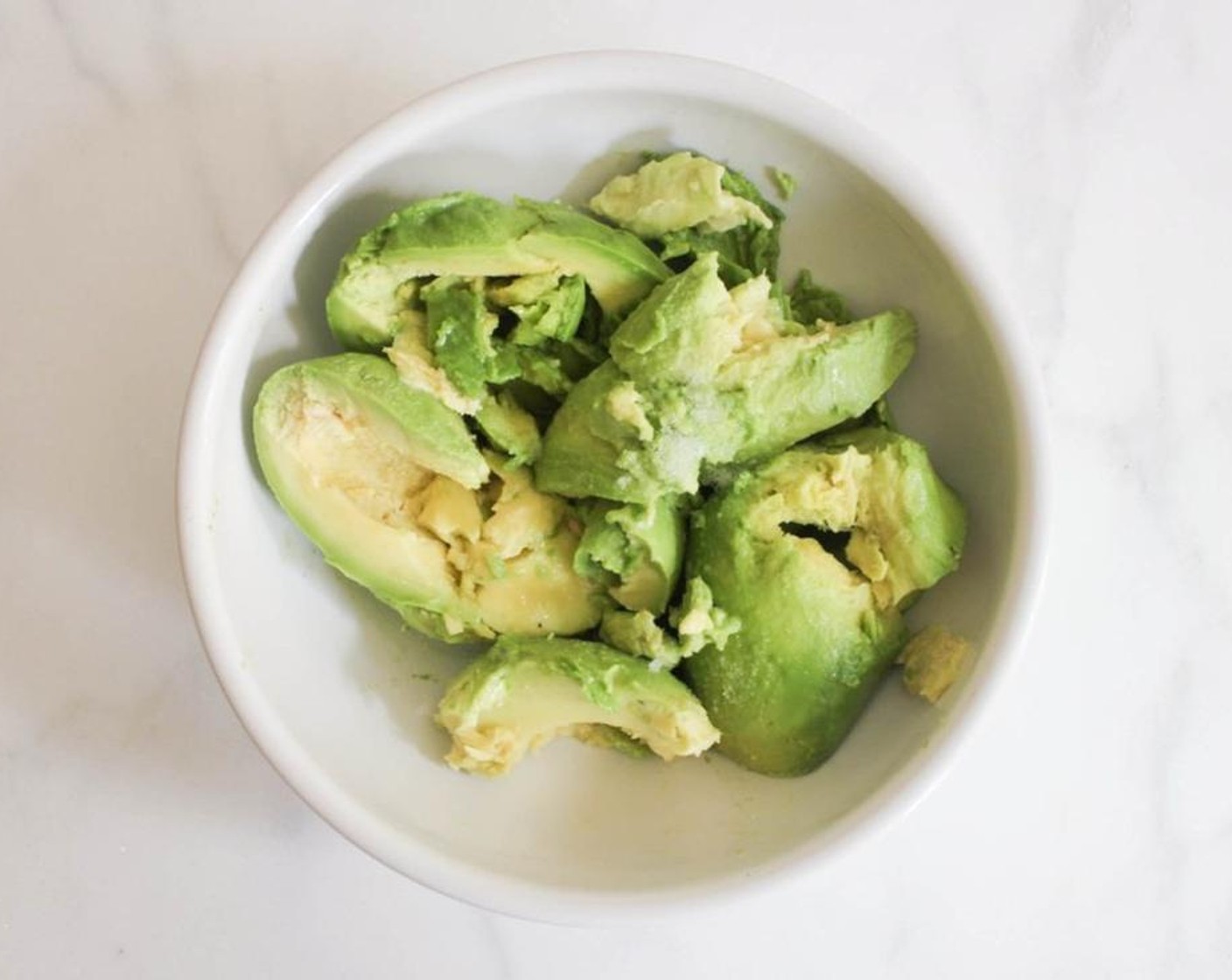 step 1 Slide your Avocados (2) in half lengthwise. Remove the pits and scoop them into a bowl. Add the juice from Lemon (1/4) and a good pinch of Fine Salt (to taste).