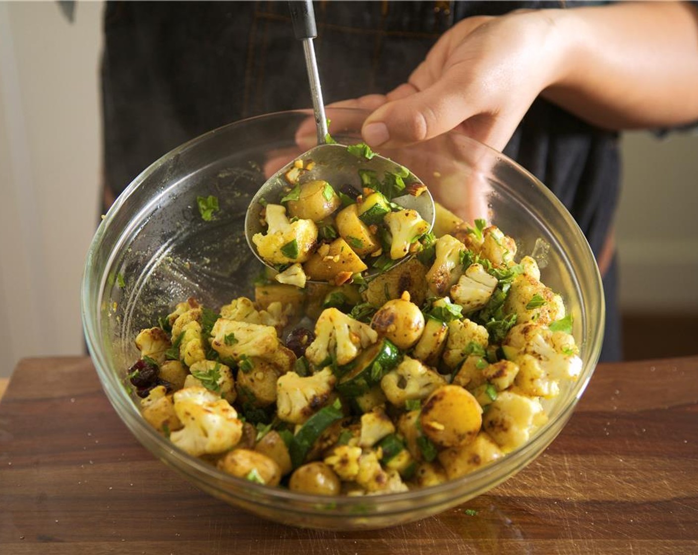 step 13 Once potatoes are cooked, remove from heat and add vegetables to the vinaigrette. Add Chopped Roasted Almonds (1/4 cup), Dried Cranberries (1 cup), basil, cilantro and chives. Toss until evenly coated. Hold for plating.