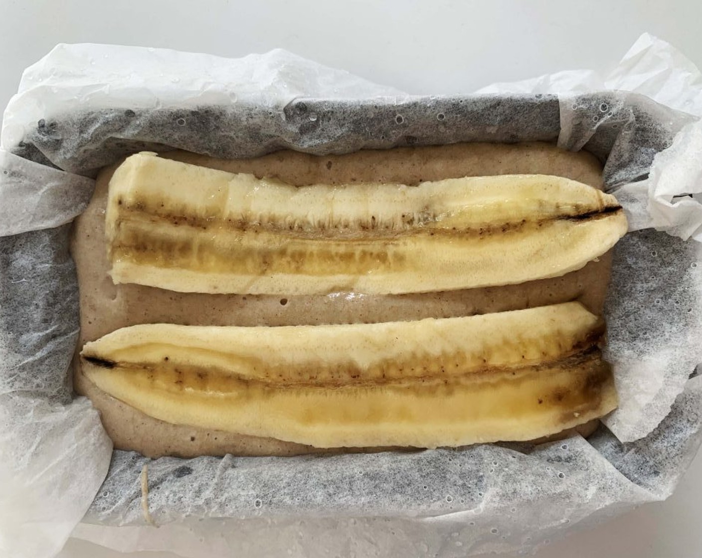 step 4 Pour the batter into the prepared loaf pan. Then, half the Banana (1) lengthwise and place it on top of the batter.