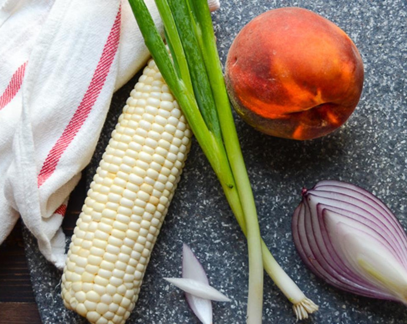 step 6 While the cornbread bakes, peel the Corn (1 ear) and remove the husk and silk. Slice the corn from the cob. Peel and pit the ripe Peach (1). Slice it into half-inch pieces. Thinly slice the Red Onion (1/4) and Scallion (1 bunch) and set aside.