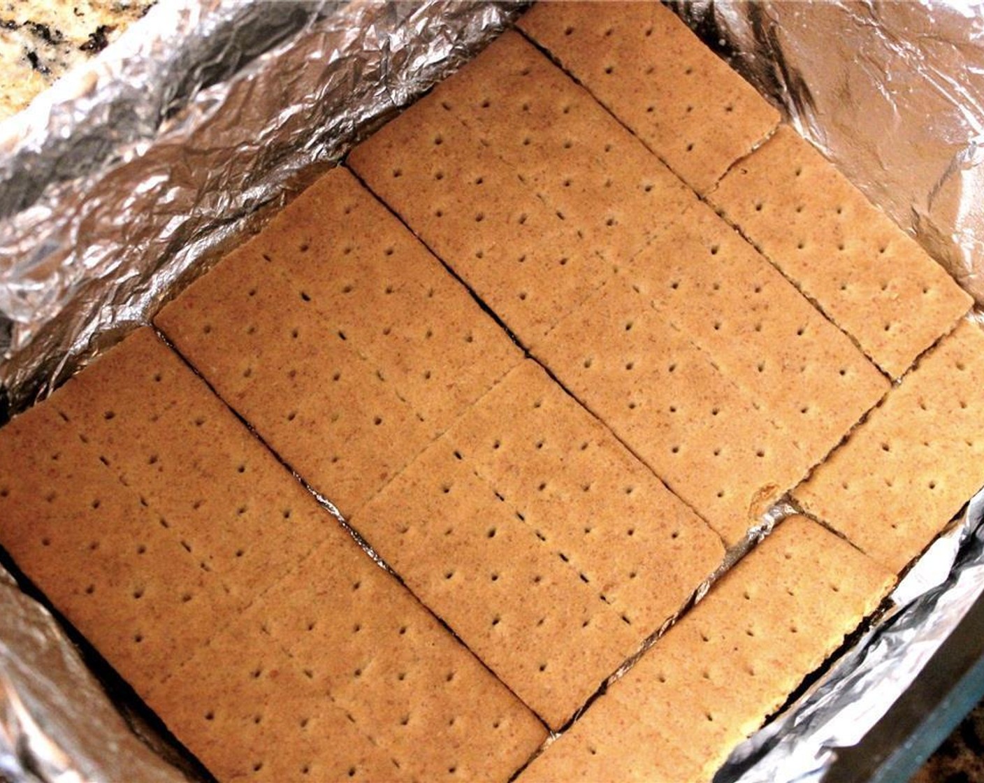 step 2 Line a baking pan with foil, making sure to hang it over the edge, and spray it with Non-Stick Baking Spray (as needed). Make a single layer of Graham Crackers (1 pckg) at the bottom of the pan.