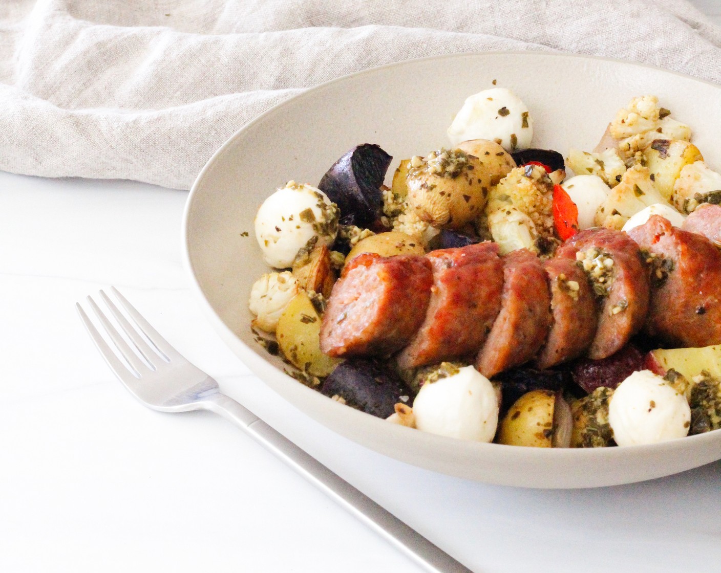 step 8 Plate the dish by spooning roasted veggies into a bowl and adding Fresh Mozzarella Pearls (1/2 cup). Stir gently to combine and top with sliced sausage. Spoon a little more pesto on top and enjoy.