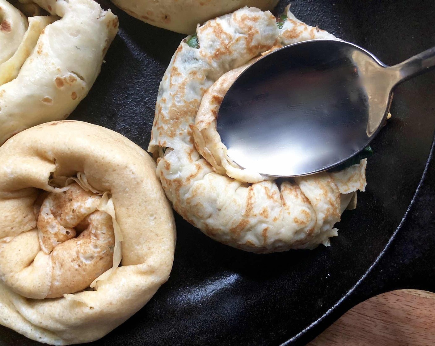 step 12 Place the rolls in a 10-inch cast-iron pan and gently make a divot in the center of each crepe roll with the back of a spoon.