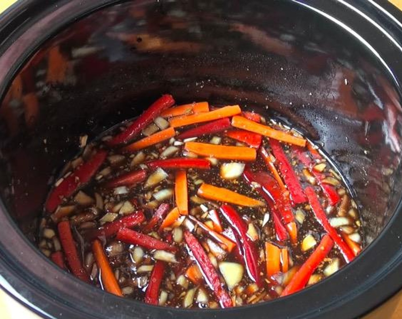 step 1 In a slow cooker, add Garlic (2 cloves), Fresh Ginger (1/2 Tbsp), Yellow Onion (1), Carrot (1), Red Bell Pepper (1), Brown Sugar (1 cup), Sweet Chili Sauce (1/4 cup), Dark Soy Sauce (1/2 cup) and Water (1 cup). Stir together. Put the lid on and cook on high for 1 hour.