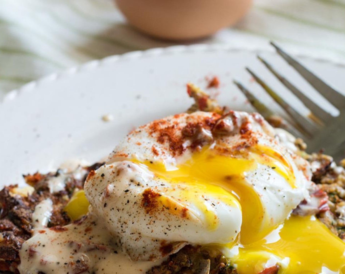 step 12 Once fritters are baked through and crispy, add to plate, top with honey lime chipotle sauce and poached eggs. Garnish with black pepper and smoked paprika to taste.