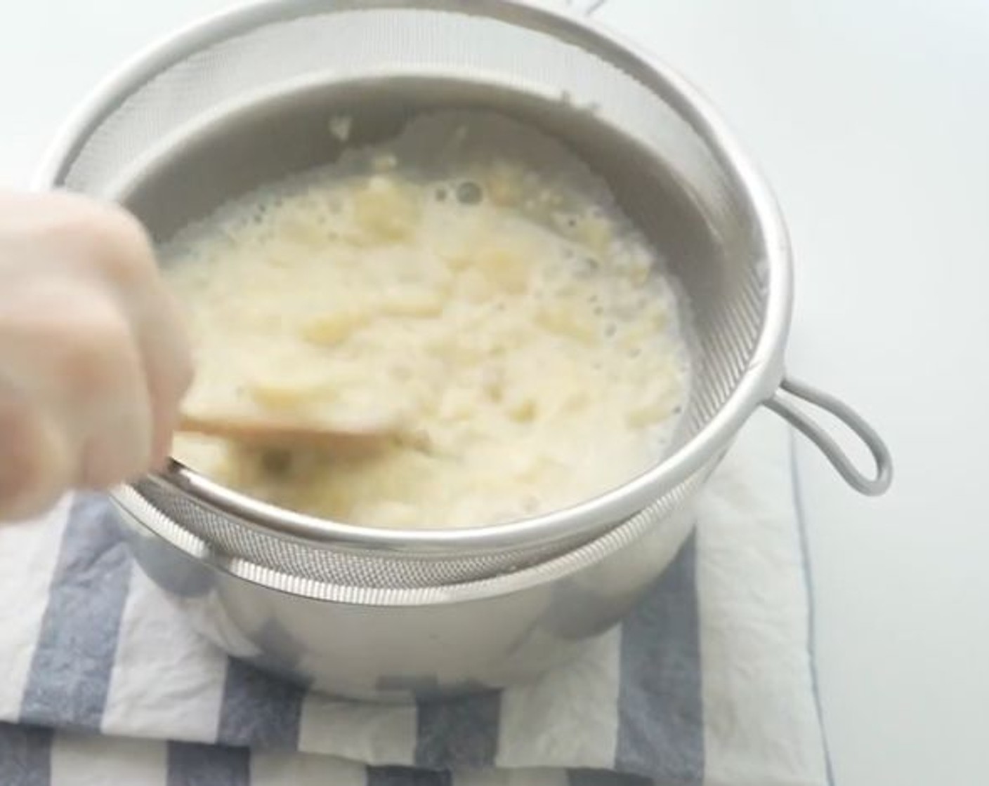 step 7 Strain the mixture through a sieve. Mash the banana lumps through the sieve with a spoon.