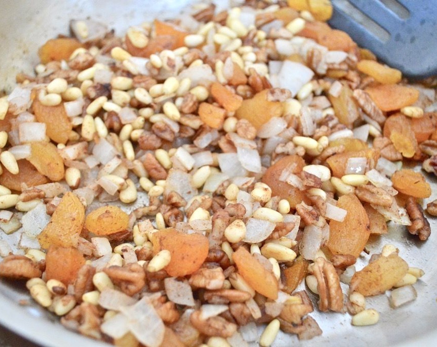 step 2 While it sits, make the filling. Heat the Olive Oil (1 dash) in a skillet over medium low heat. Then add the Onion (1), Pine Nuts (1/3 cup), Pecans (1/3 cup), Dried Apricot (1/3 cup), and Ground Cinnamon (1/2 tsp) in and let them get fragrant for a couple of minutes while you stir it.