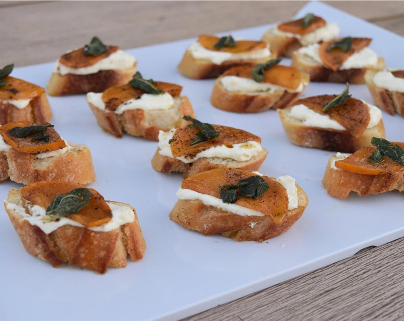 step 9 Spread a dollop of whipped ricotta on each crostini, layer on a slice or two of persimmon, drizzle with a small bit of extra butter, and top with a crisped sage leaf. Serve and enjoy!