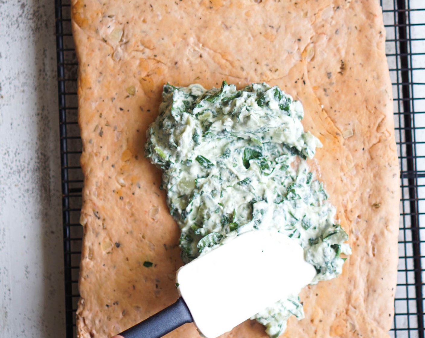 step 11 Punch the dough down and divide in half. Roll each half into a rectangle about 3/4 inch thick. Spread each with the spinach filling. Roll up each rectangle into a jelly roll like shape and place on greased baking sheets. Cover loosely with plastic wrap and let it rise for 1 hour.