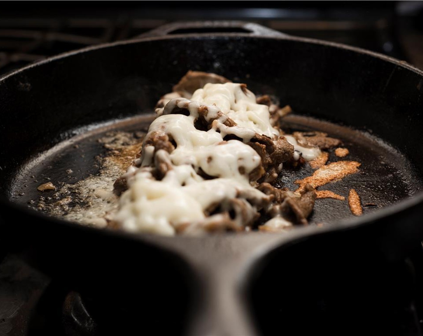 step 7 Form the beef into the approximate length of the hoagie roll. Top with a ¼ of the caramelized onions and ¼ of the grated Provolone Cheese (3 cups). Add a tablespoon of the reserved marinade. Cover the pan with a lid and cook about a minute.
