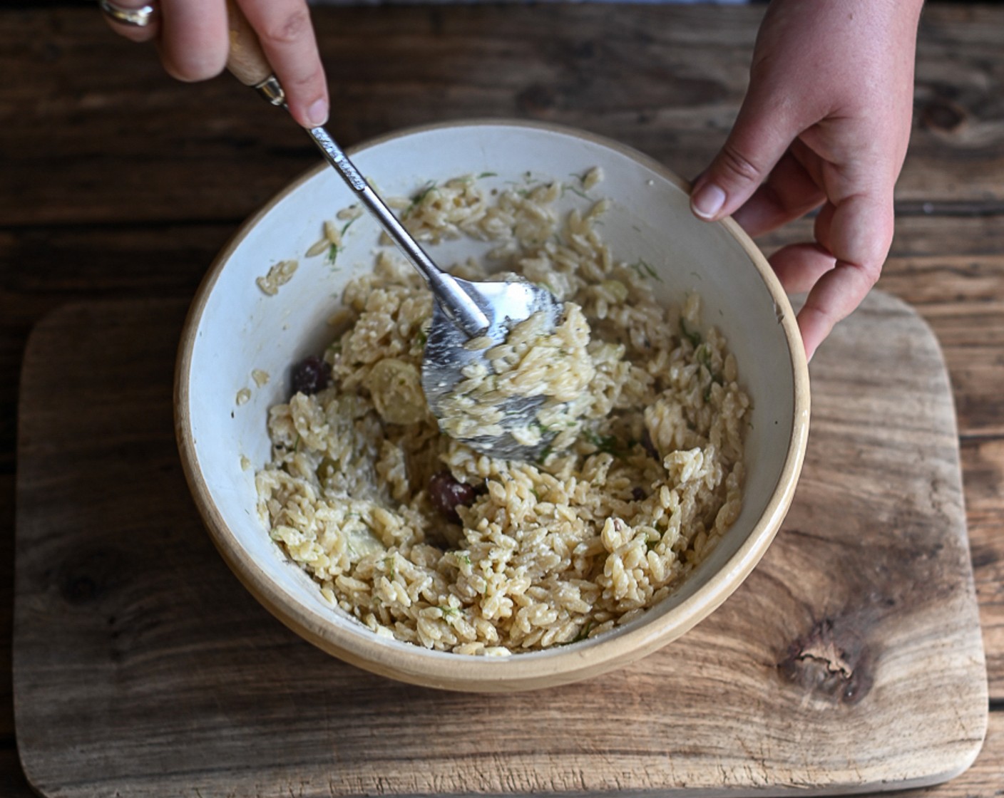step 8 Using tongs, transfer the cooked fennel, feta, and olives from the ovenproof dish to the orzo and combine. Finely chop the reserved fennel leaves and add to the mixture.