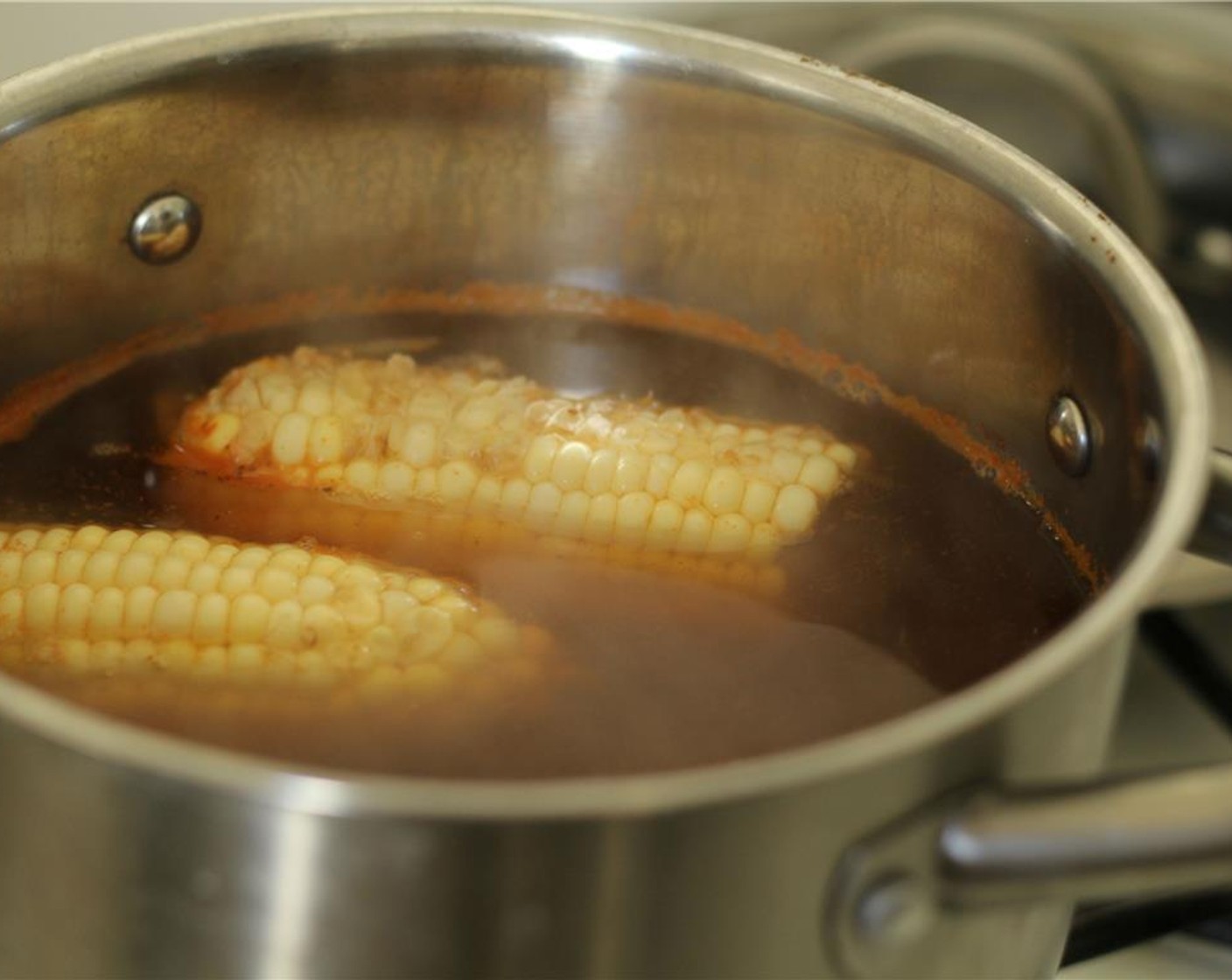 step 2 Cut the Corn (1 ear) in half. Add the Beer (12 fl oz), Water (3 cups), Onion (1/2), Garlic (1/2 clove), Old Bay® Seasoning (1 Tbsp) and corn into a large pot and simmer for 3 minutes uncovered.