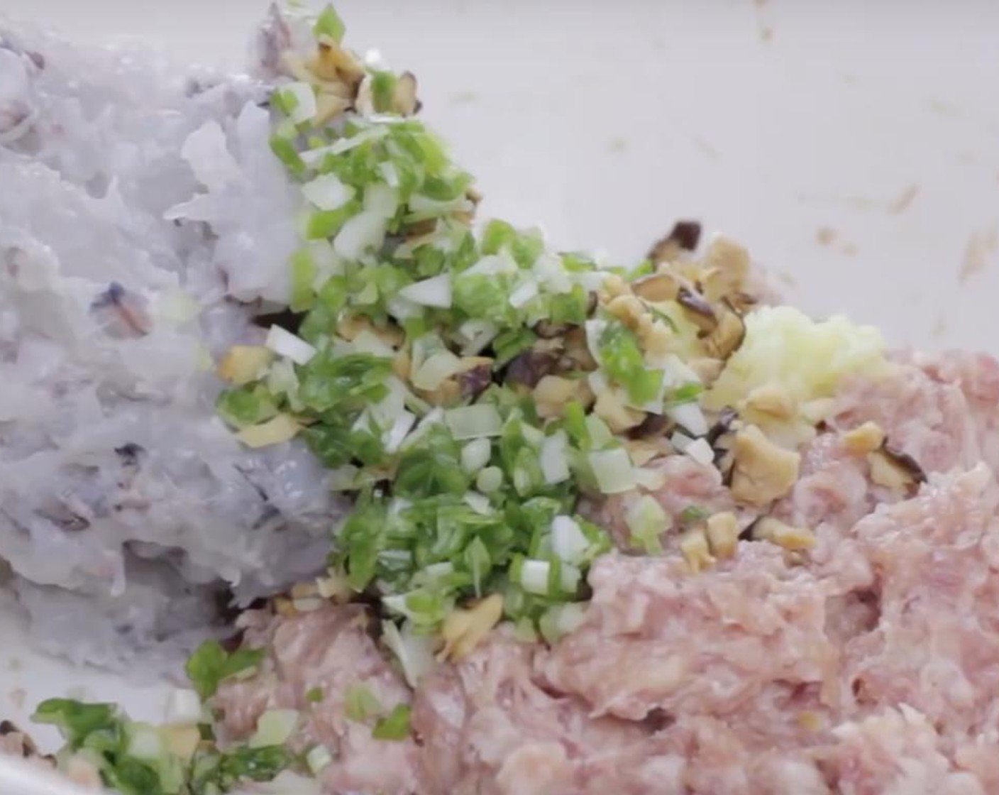 step 7 Put shrimp and pork paste in the mixing bowl, add the Scallion (3/4 stalk), Fresh Ginger (2 slices) and mushroom. Squeeze and mix the ingredients with your hands until blended. Remember to throw the paste against the mixing bowl!