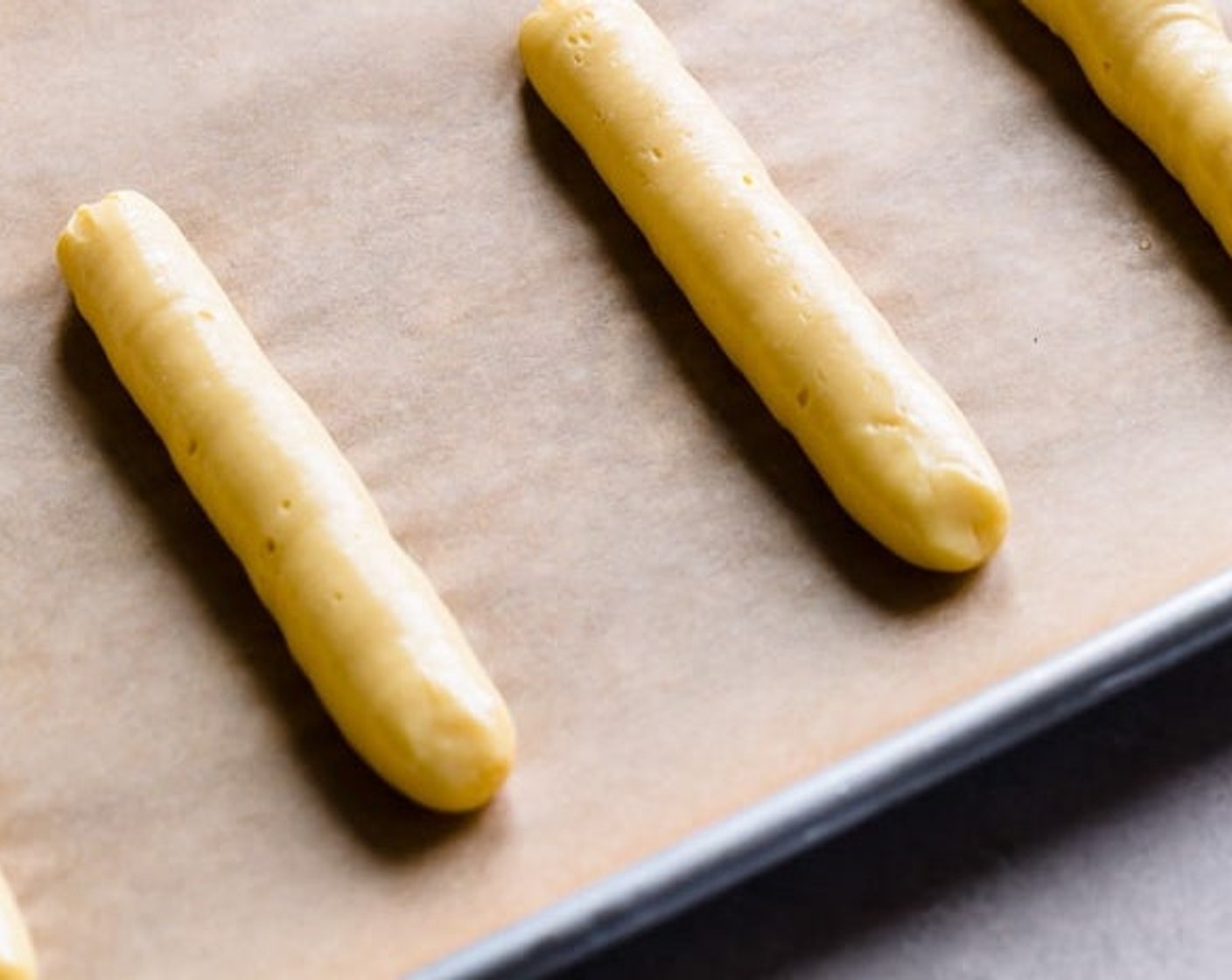 step 8 To bake pastry shells, transfer the batter into a large pastry bag and pipe into 4-inch strips or 2-inch rounds 3 inches apart. Level peaked tops with a wet fingertip.