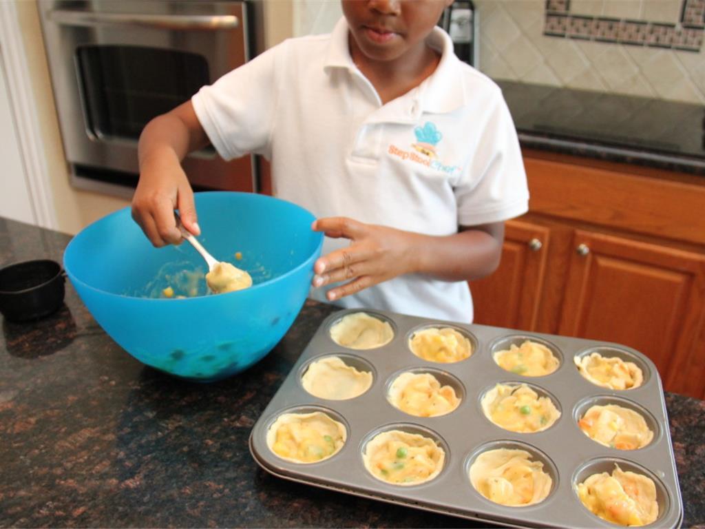 Step 3 of Muffin Tin Pot Pie Recipe: Spoon the filling mix into the cups with about 1 to 2 tablespoons per cup.
