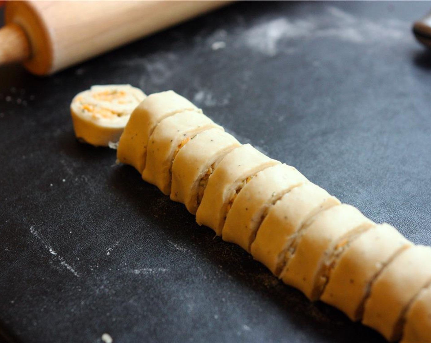 step 10 Carefully roll up the dough along one of the long sides to form a long, narrow log. Cut the log into 3/4″ segments using a sharp serrated knife, which should yield 32-36 pieces.