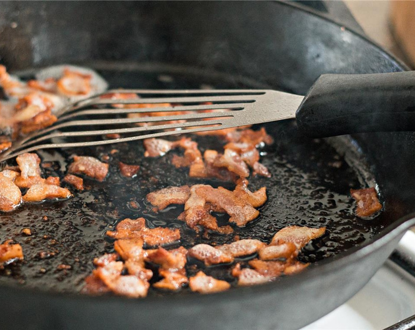 step 6 In a large skillet over medium heat, render the fat from the bacon until it becomes crispy. Remove the bacon with a slotted spoon to drain on paper towels.