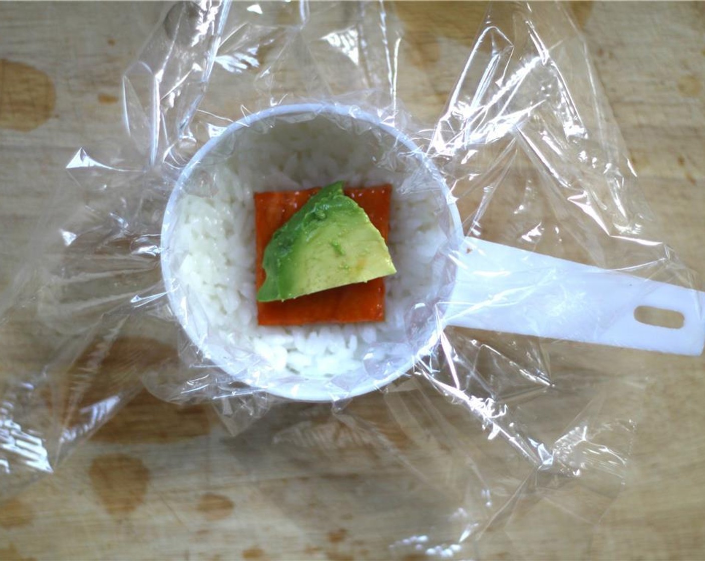 step 11 LIne a measuring cup with plastic wrap for easy removal. With wet hands, press about 2 tbsp. of rice into the mold. Layer in a piece of sweet potato dipped in the remaining teriyaki sauce, along with a piece of avocado.