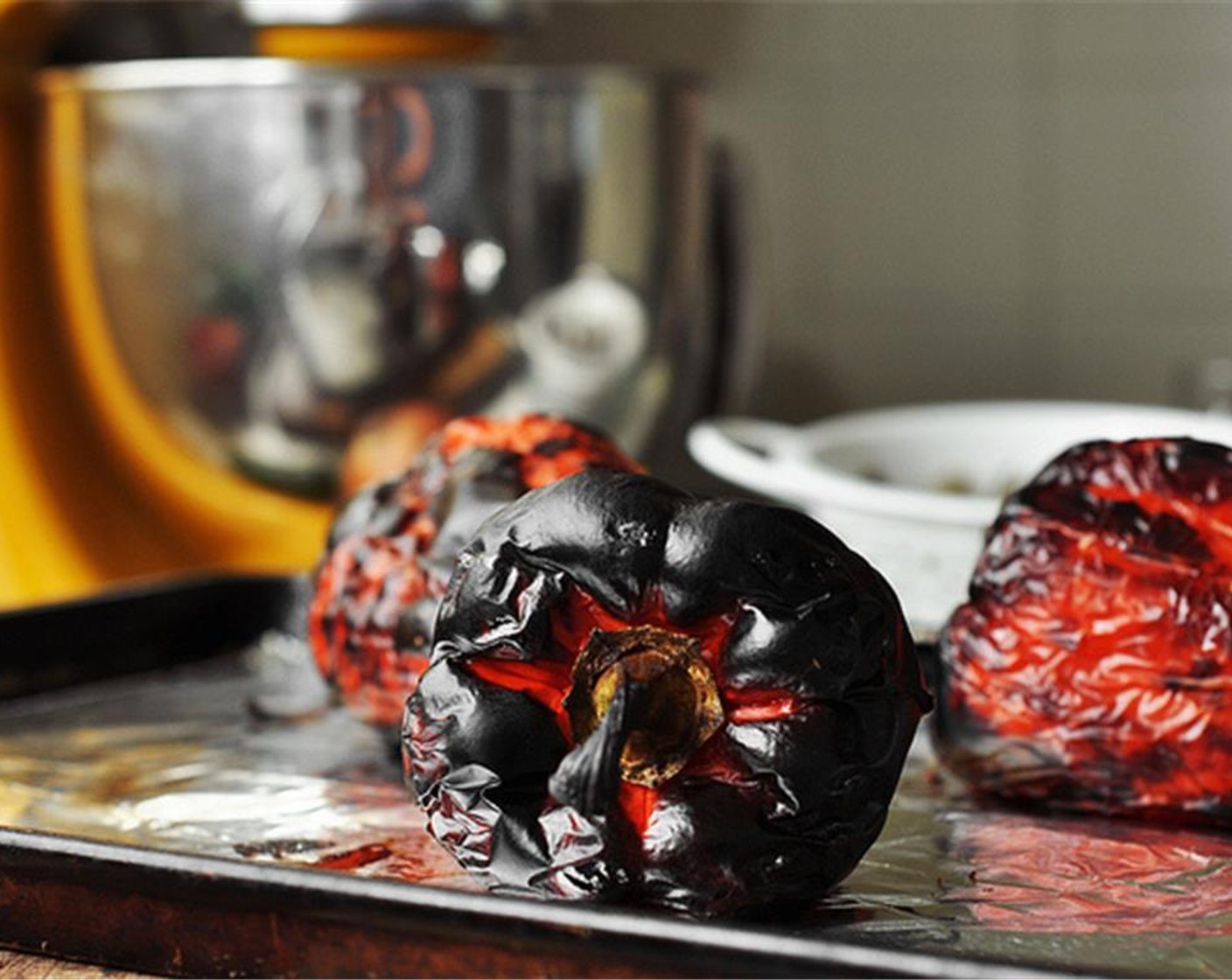 step 4 Place the Red Bell Peppers (3) on a baking sheet lined with foil paper. Place under the broiler and char the skins, turning often to evenly blacken. About 8 to 10 minutes. Remove from the oven and transfer the peppers to a bowl.