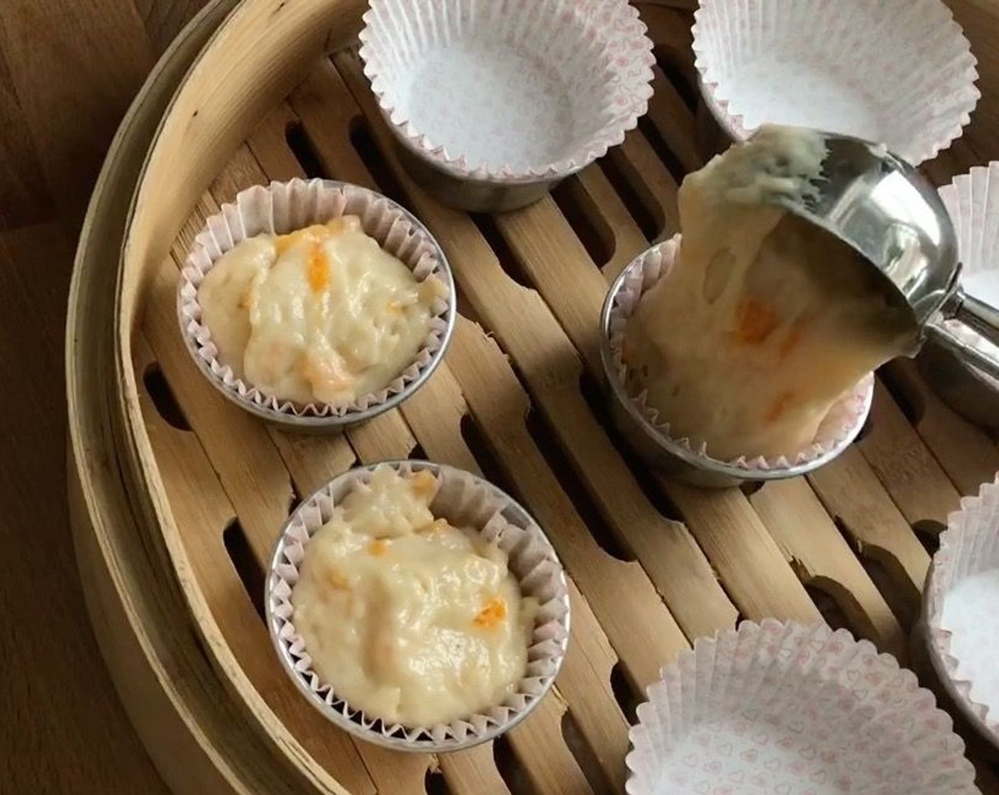 step 13 Using an ice-cream scoop, fill the mixture to the brim. Fill the batter up to the rim of pudding cup liners to allow the muffins to "smile" when steamed. Place over steamer.