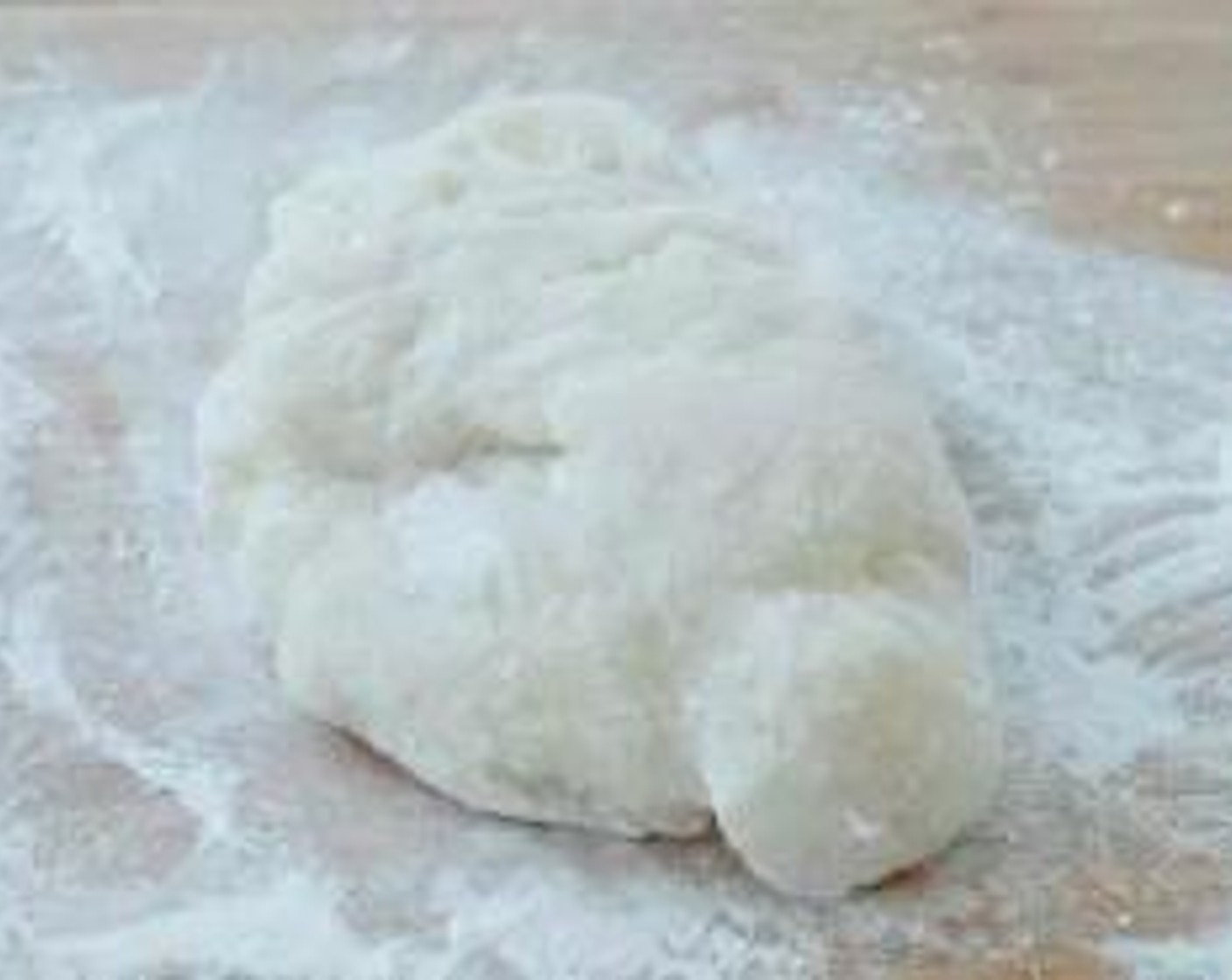 step 4 Sprinkle some cooked glutinous rice flour on a table, place the dough on top and coat with more glutinous rice flour. Place a parchment paper on top and roll it.